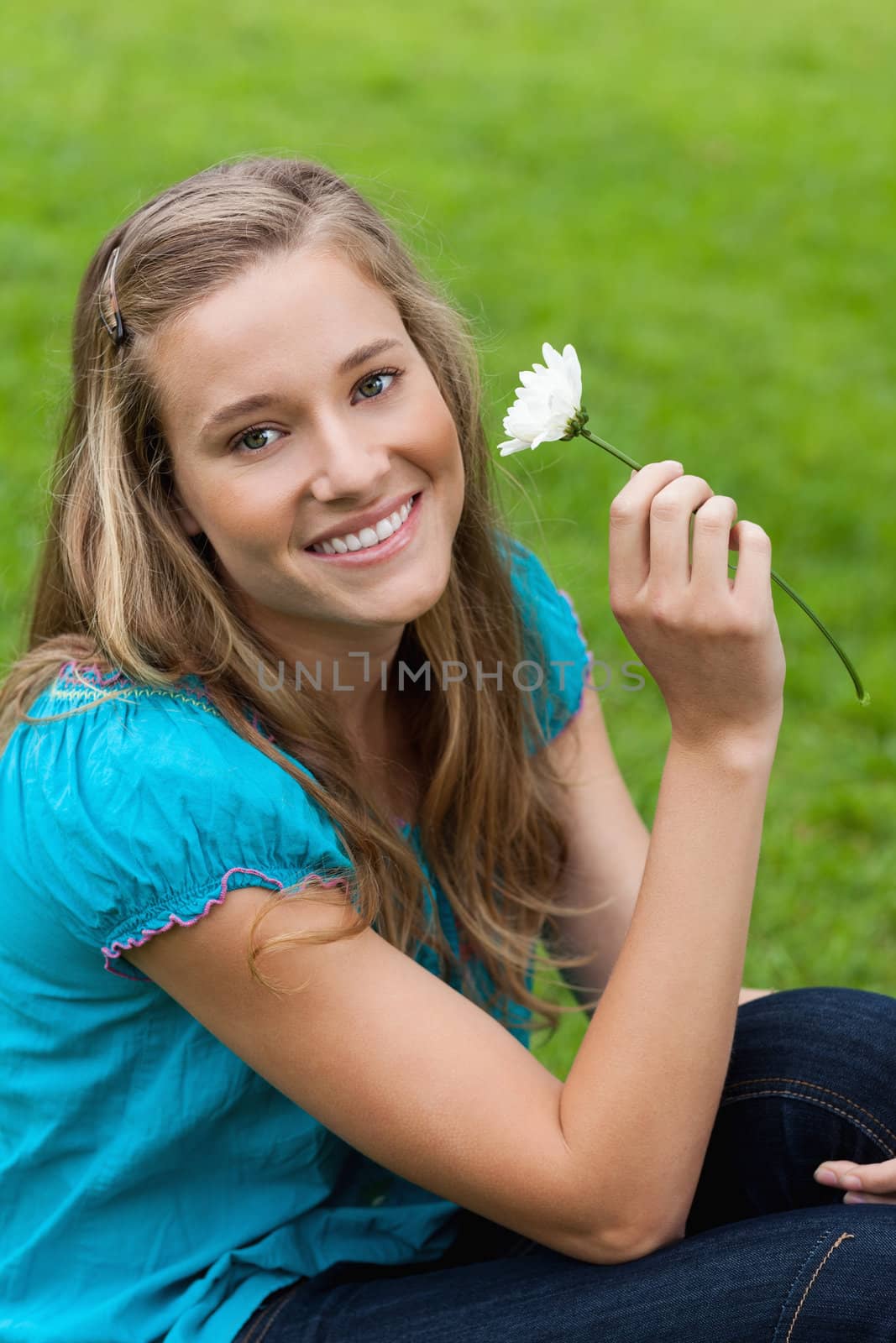 Young smiling woman holding a flower while sitting down by Wavebreakmedia