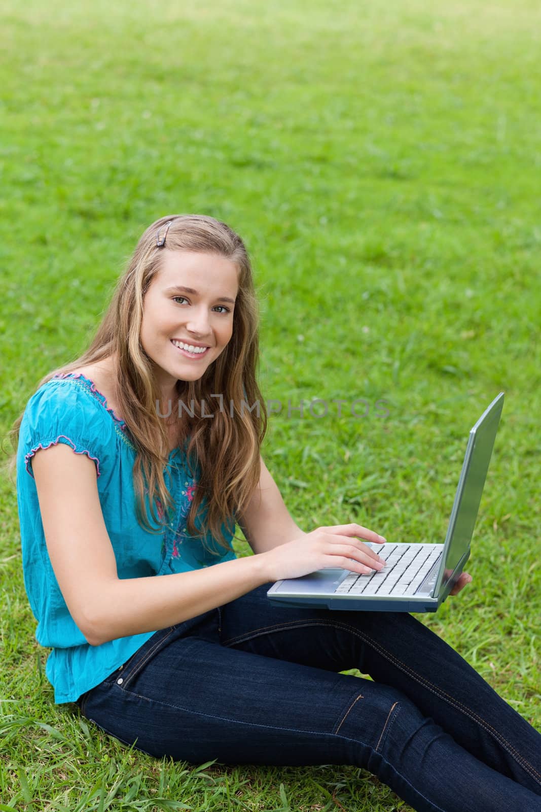 Young beautiful girl looking at the camera while using her laptop in the countryside