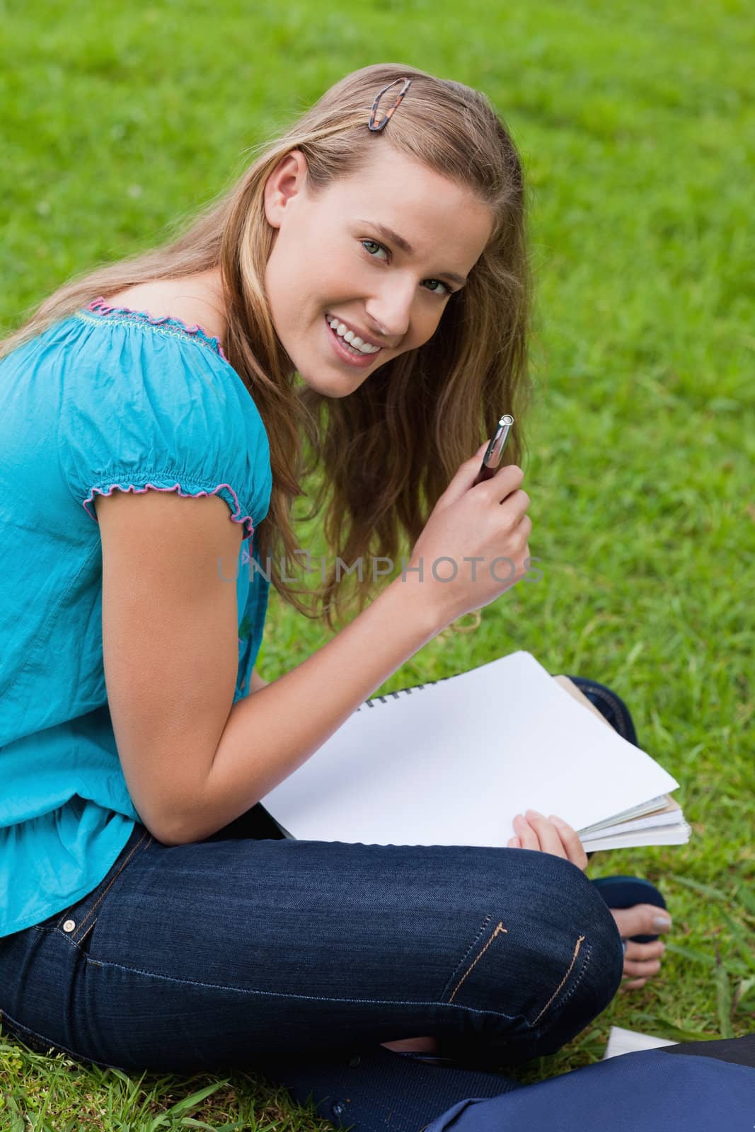 Smiling attractive girl holding her pen while looking straight at the camera