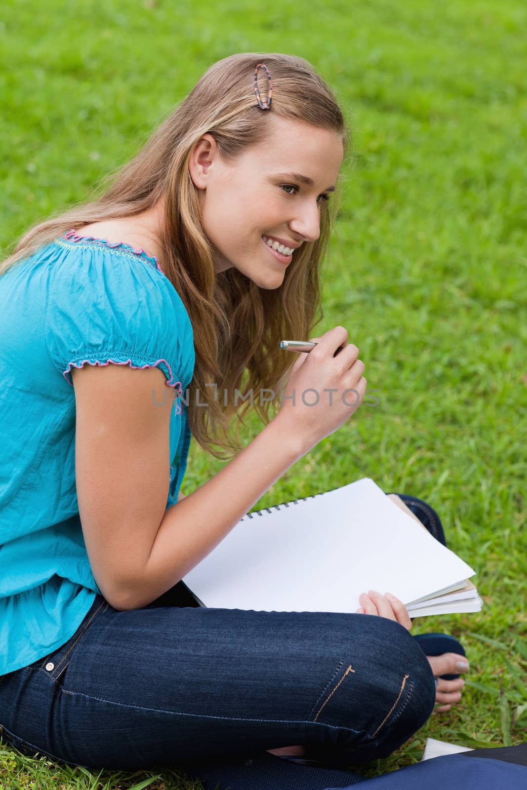 Smiling student looking towards the side while seriously writing on her notebook