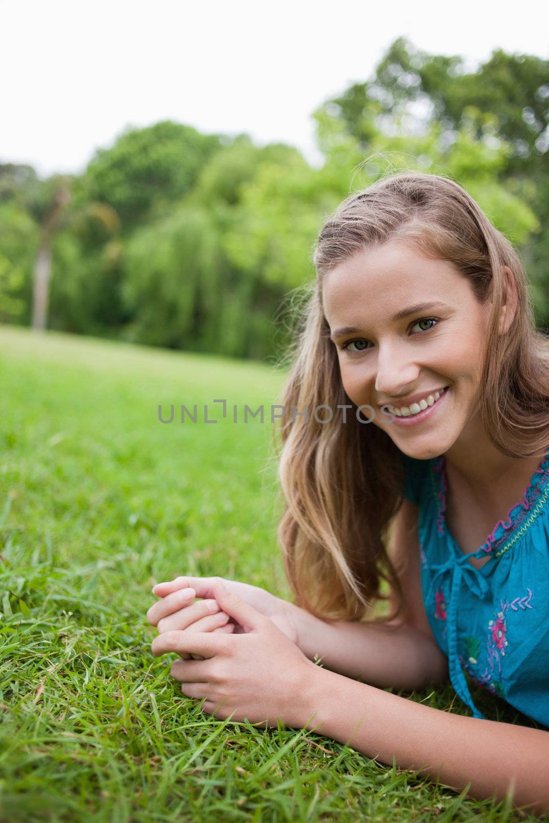 Young smiling woman lying on the grass in a public garden by Wavebreakmedia