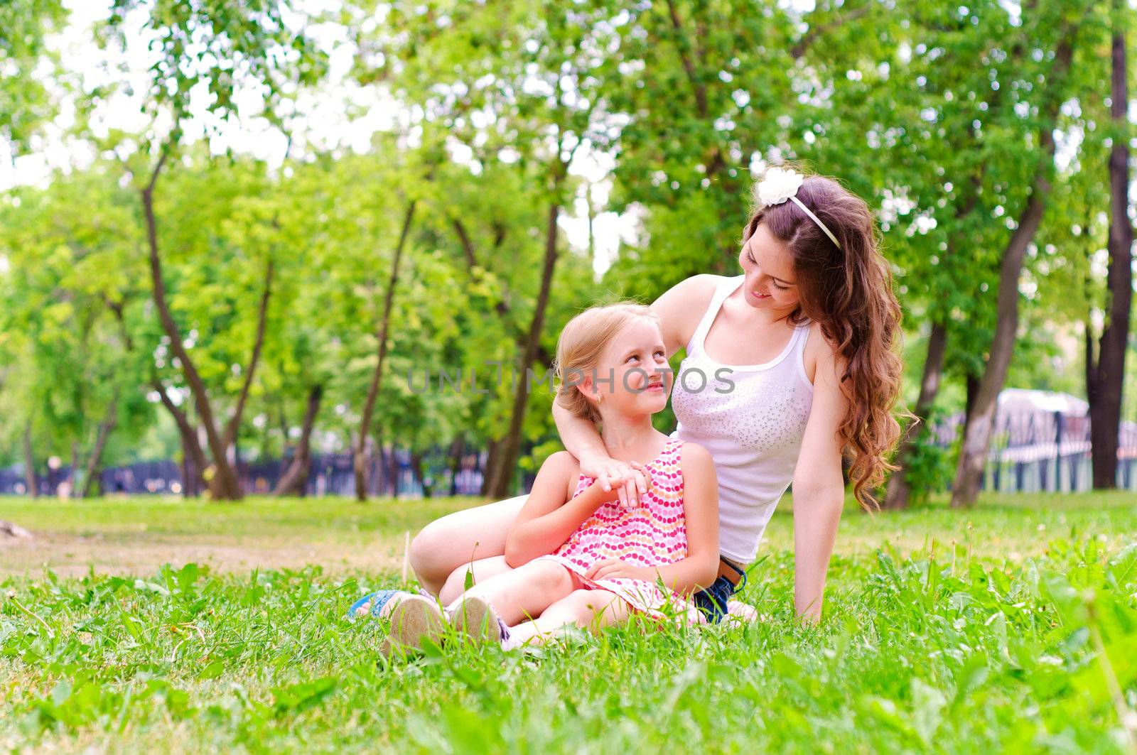 mother and daughter sitting together on the grass, and spend time with family