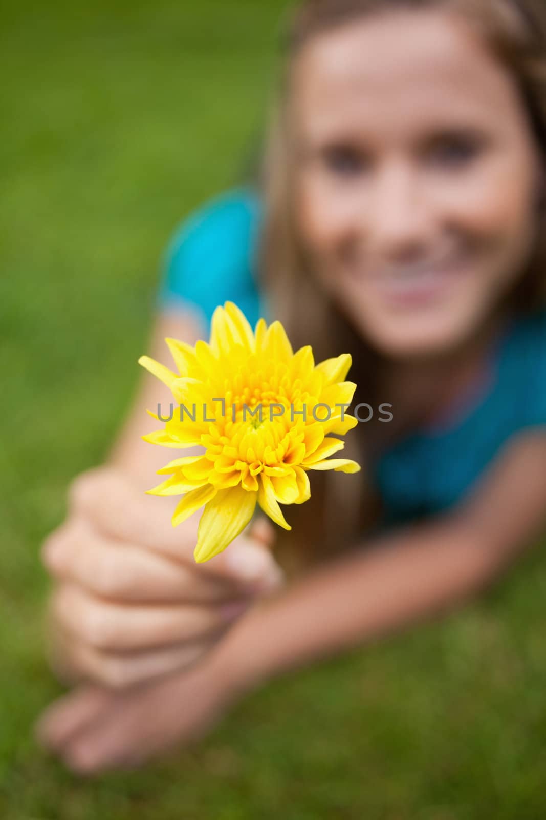 Yellow flower held by a young girl lying on the grass by Wavebreakmedia