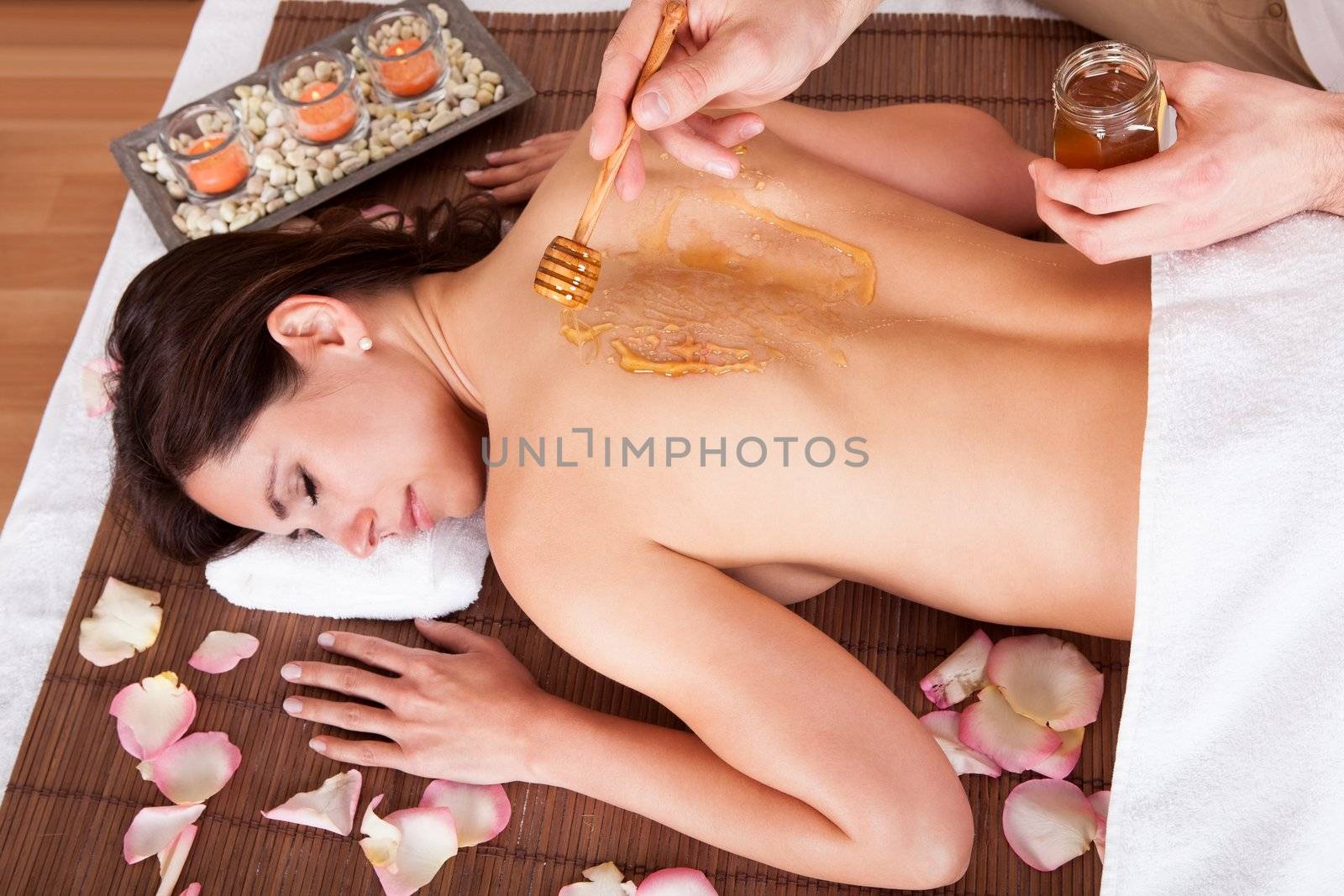Beautiful young woman receiving spa treatment with honey