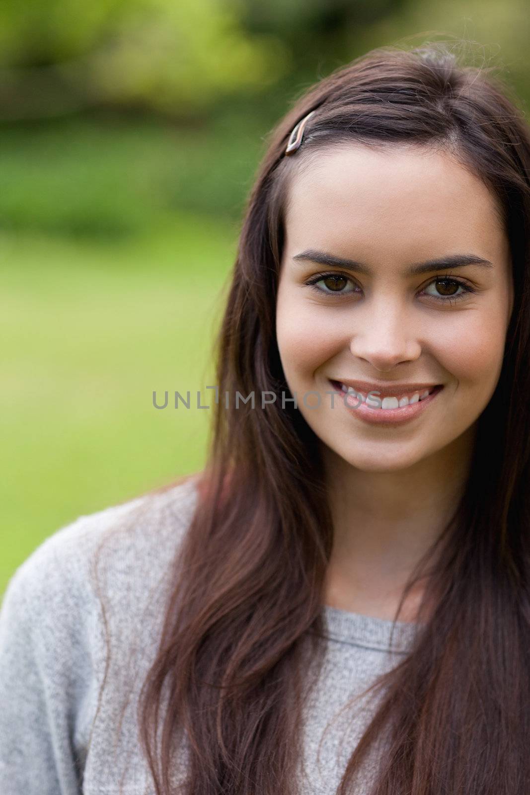 Attractive girl looking straight at the camera while standing in a park and smiling