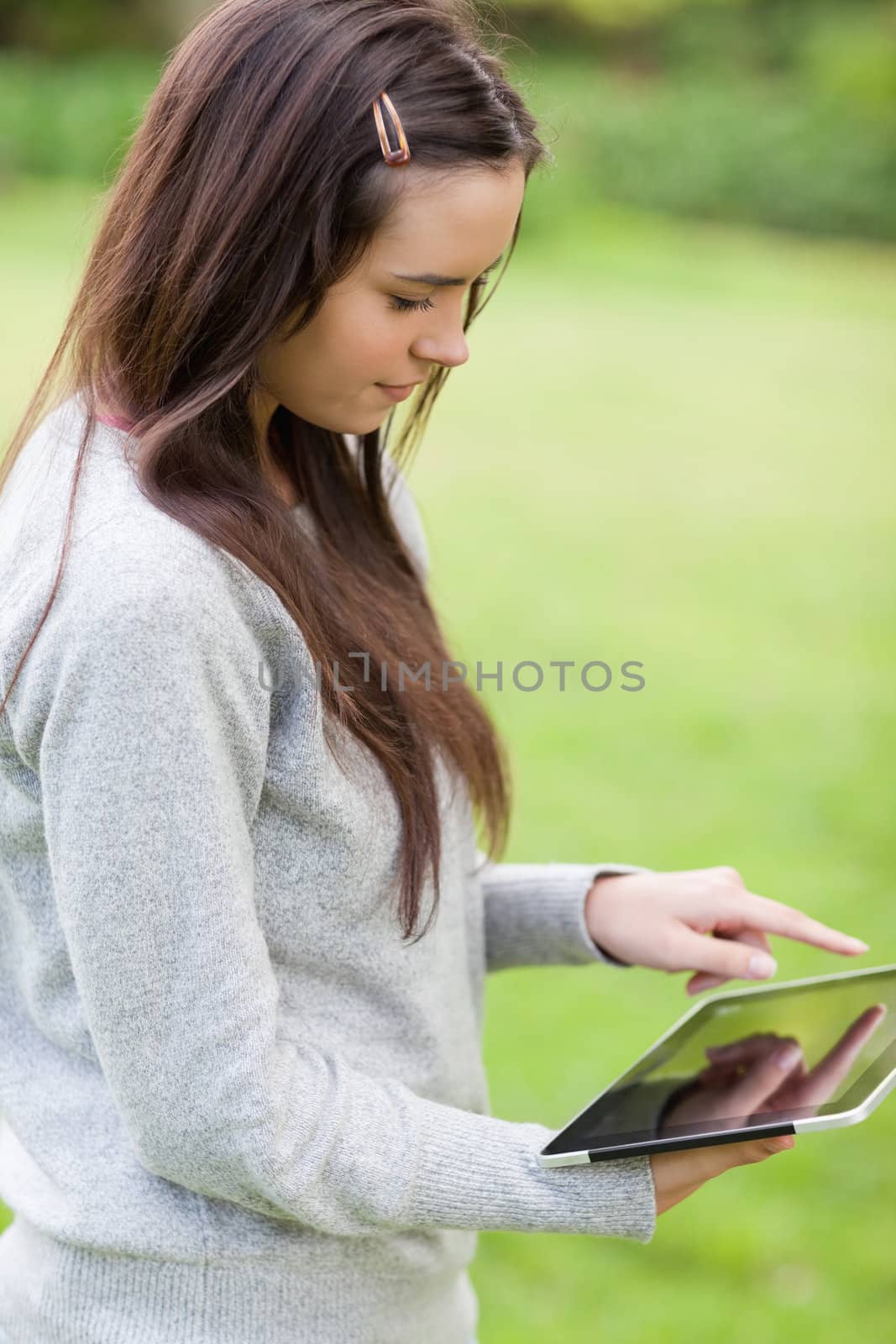 Young relaxed girl standing up in the countryside while holding a tablet computer