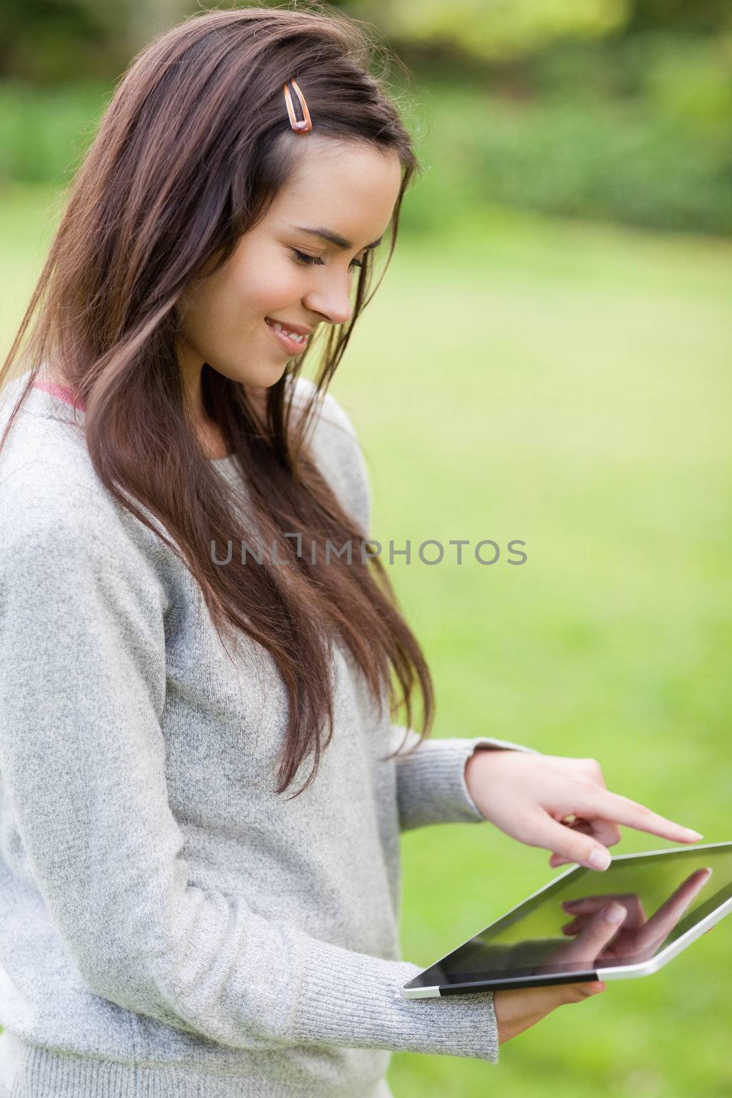 Young smiling girl using her tablet computer while standing in a by Wavebreakmedia