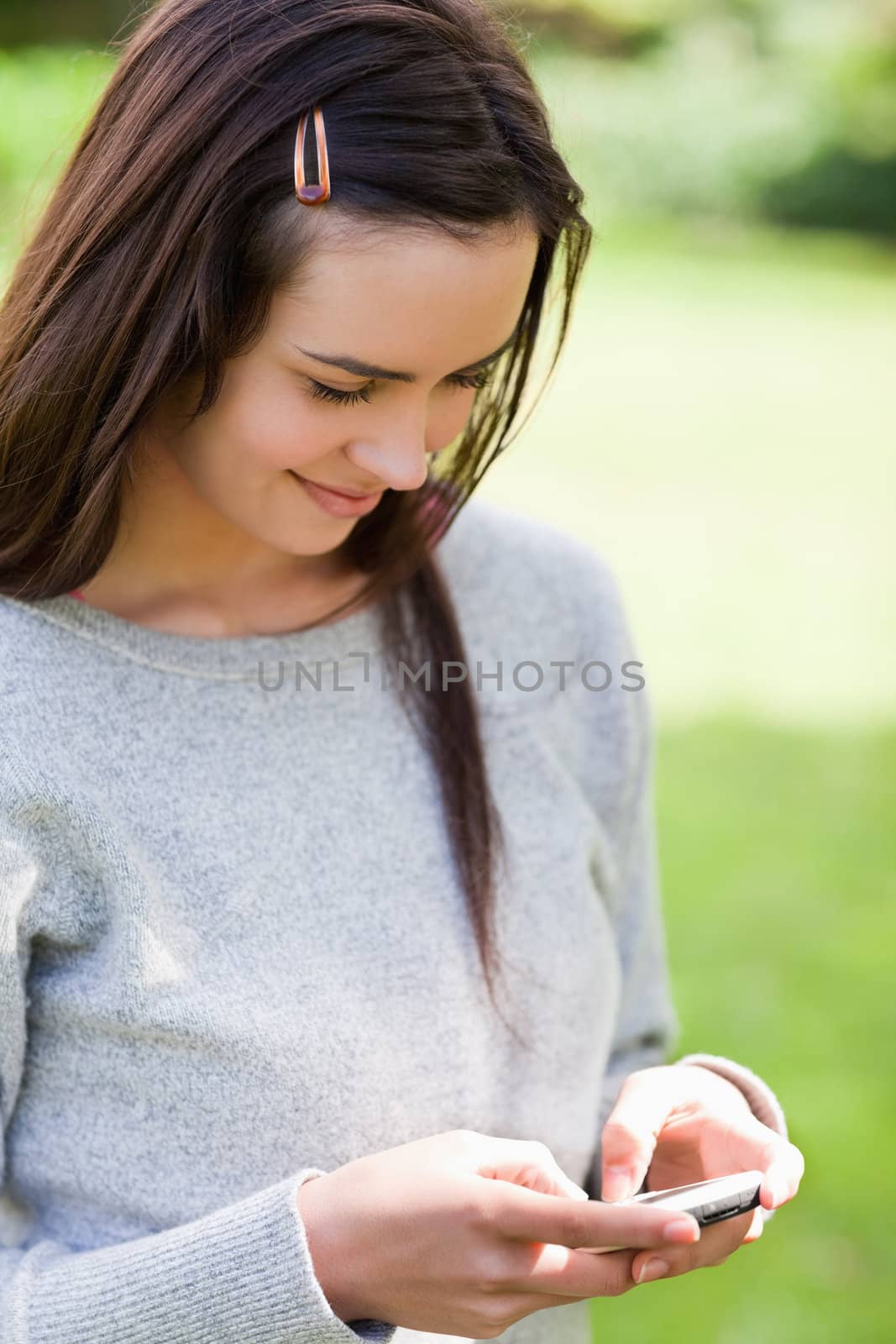 Relaxed young girl sending a text while standing in the countryside