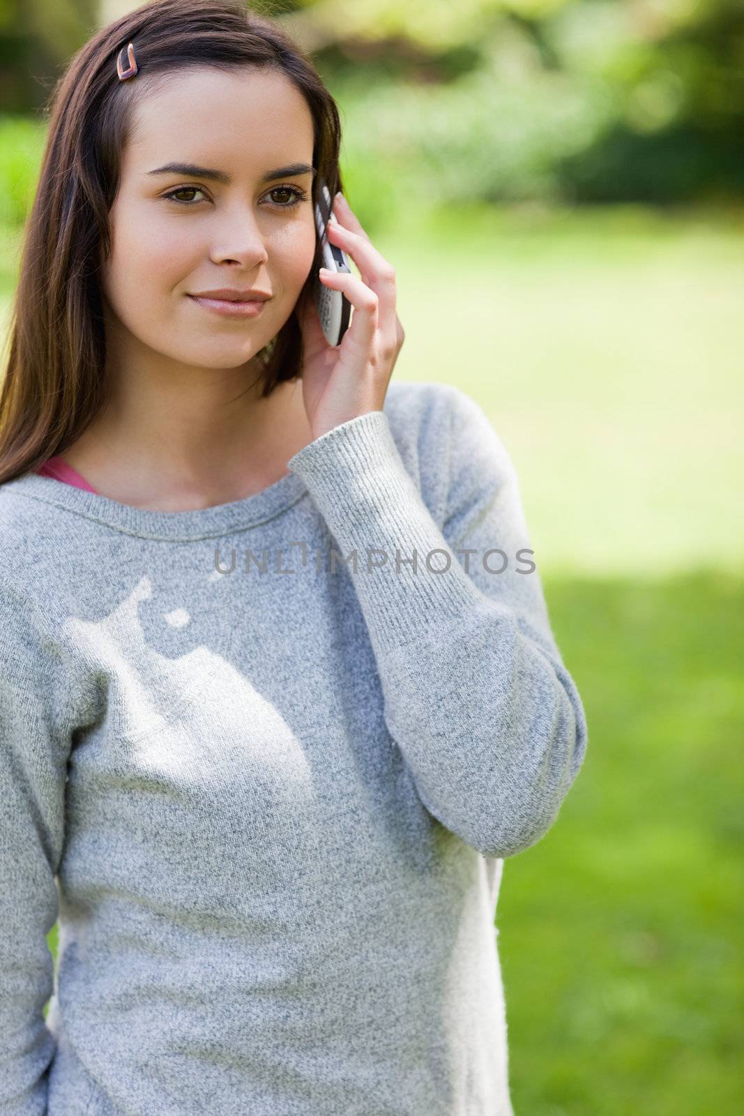 Young serious woman calling with her cellphone while standing in by Wavebreakmedia