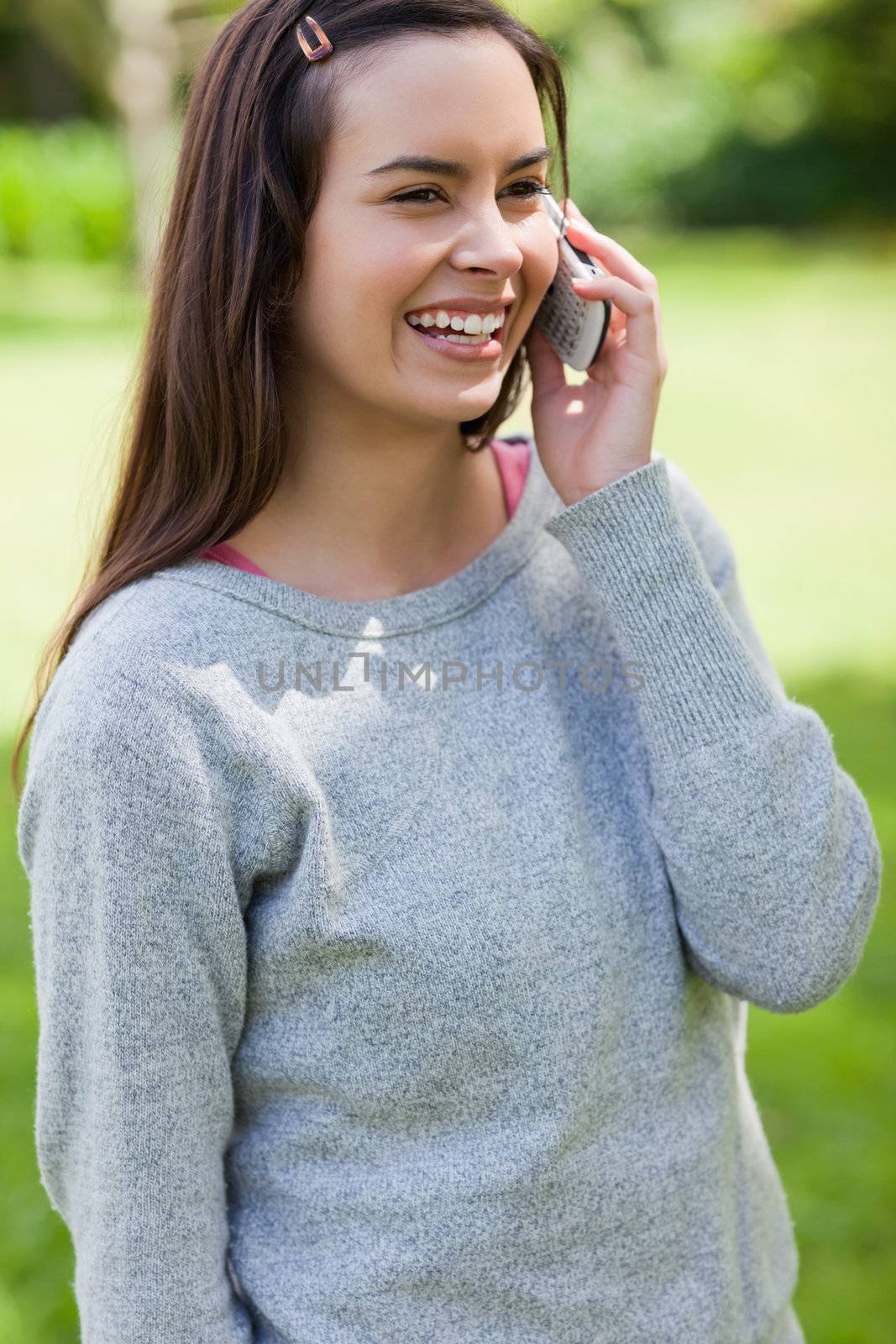 Young girl laughing while talking on the phone in a park by Wavebreakmedia