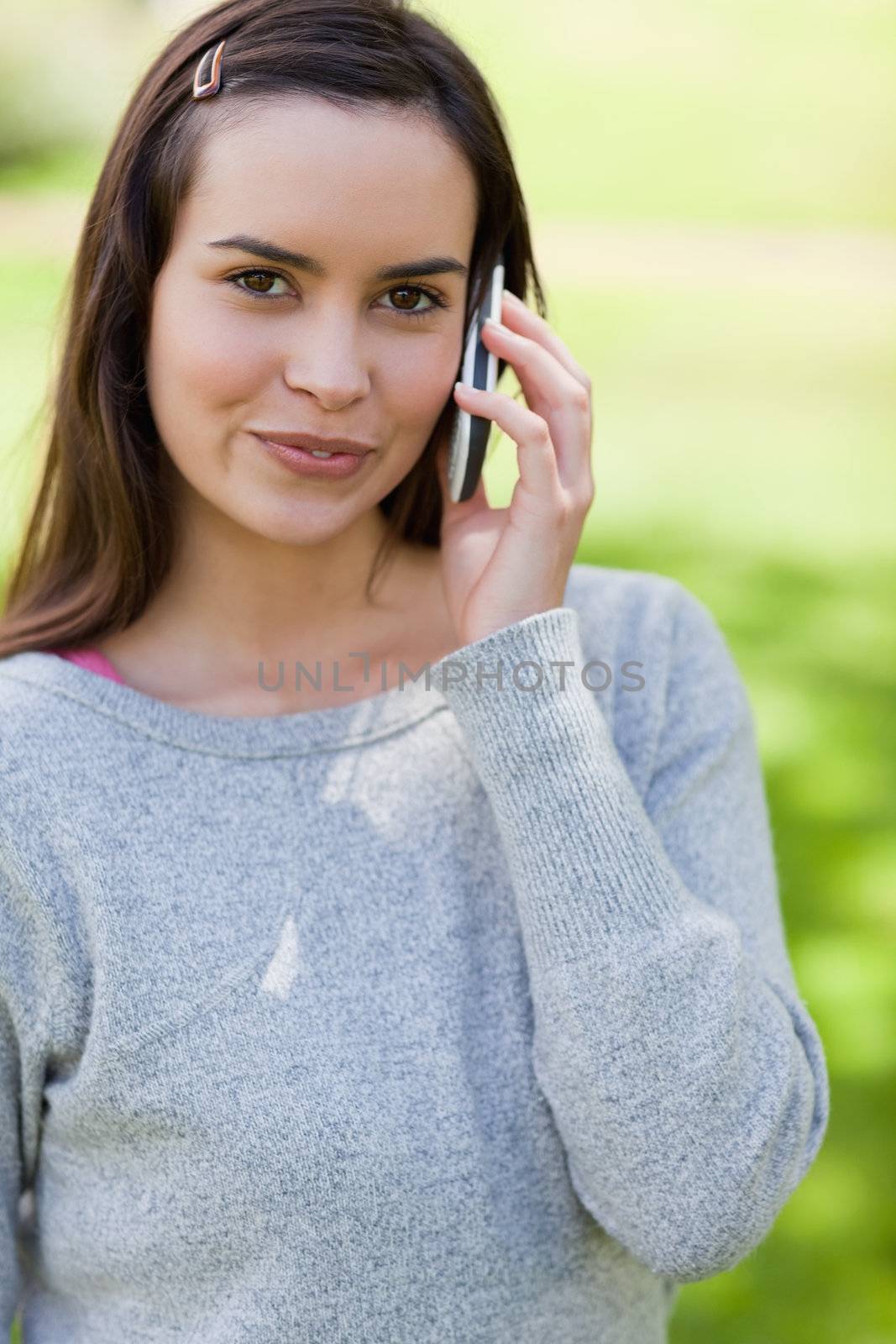 Peaceful young adult using her cellphone while standing in the countryside