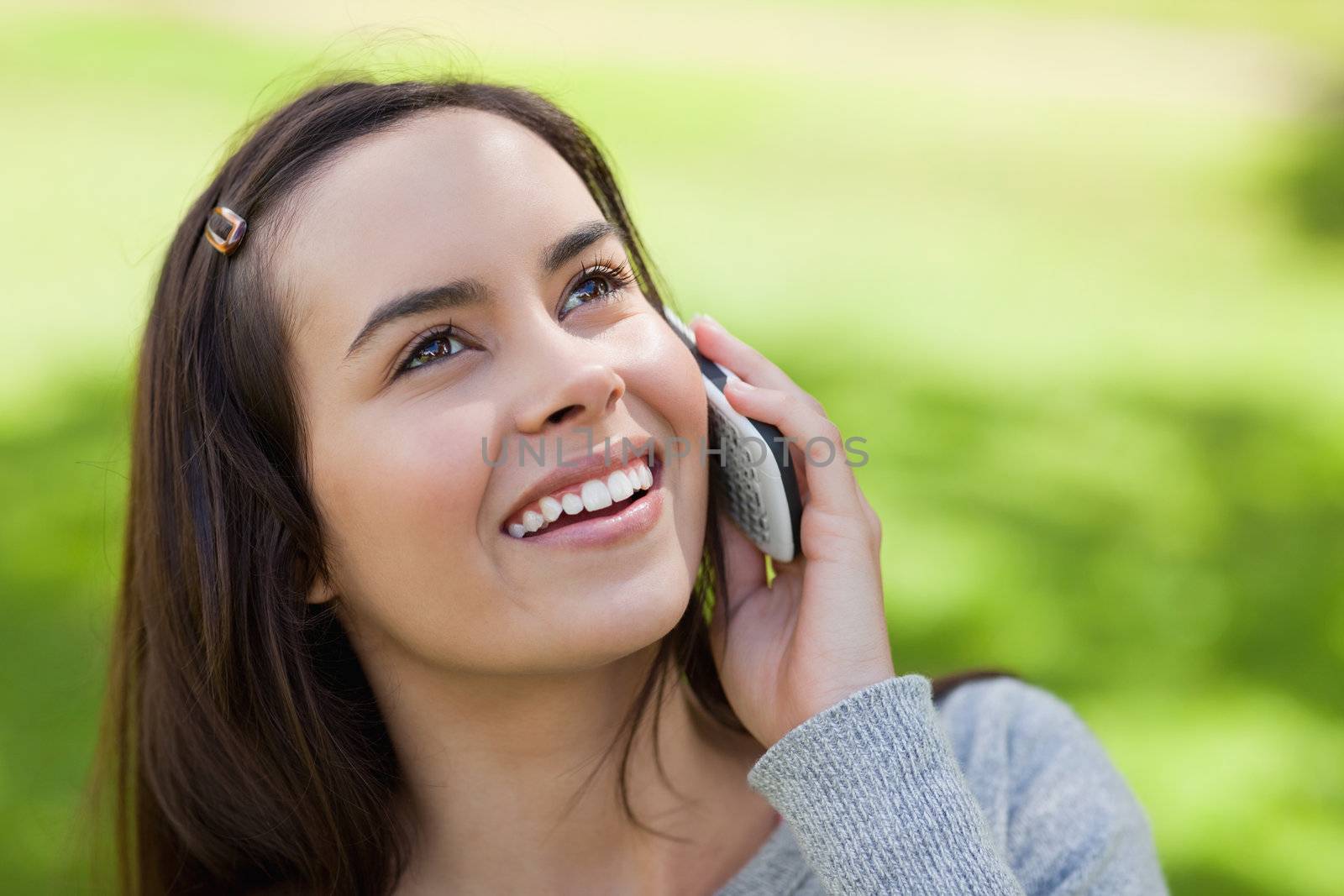 Young smiling woman looking up while talking on the phone by Wavebreakmedia
