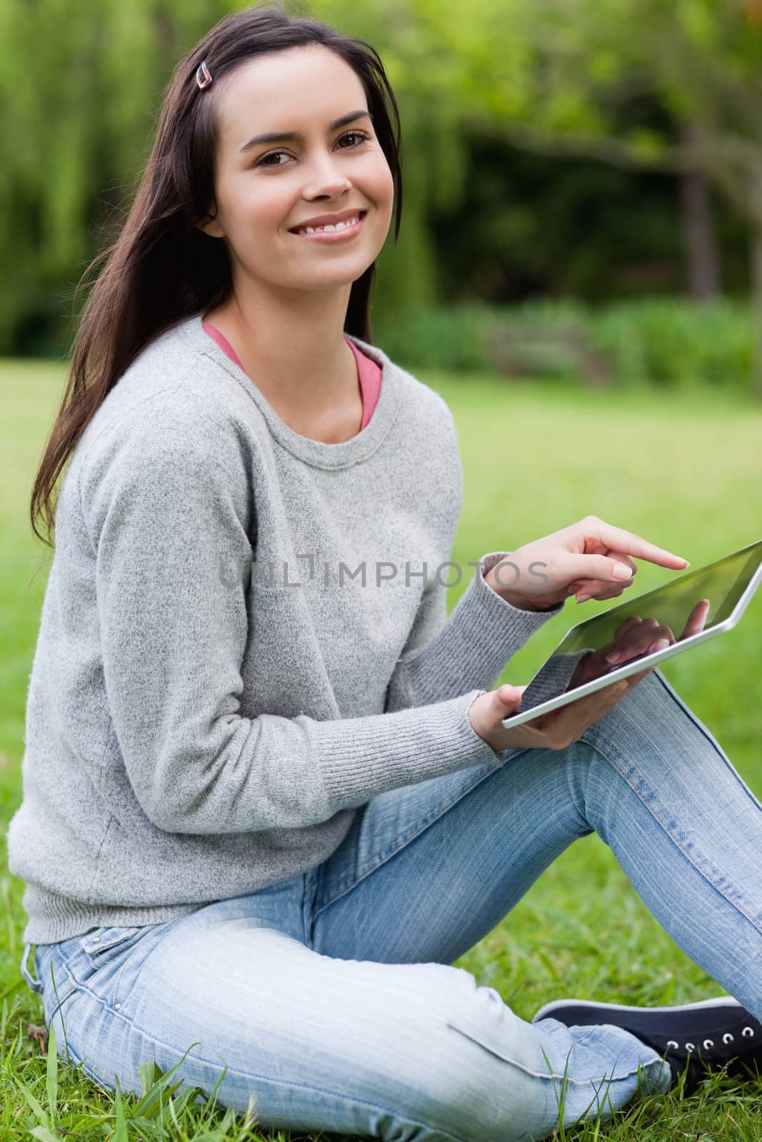 Young smiling girl looking straight at the camera while using her tablet computer