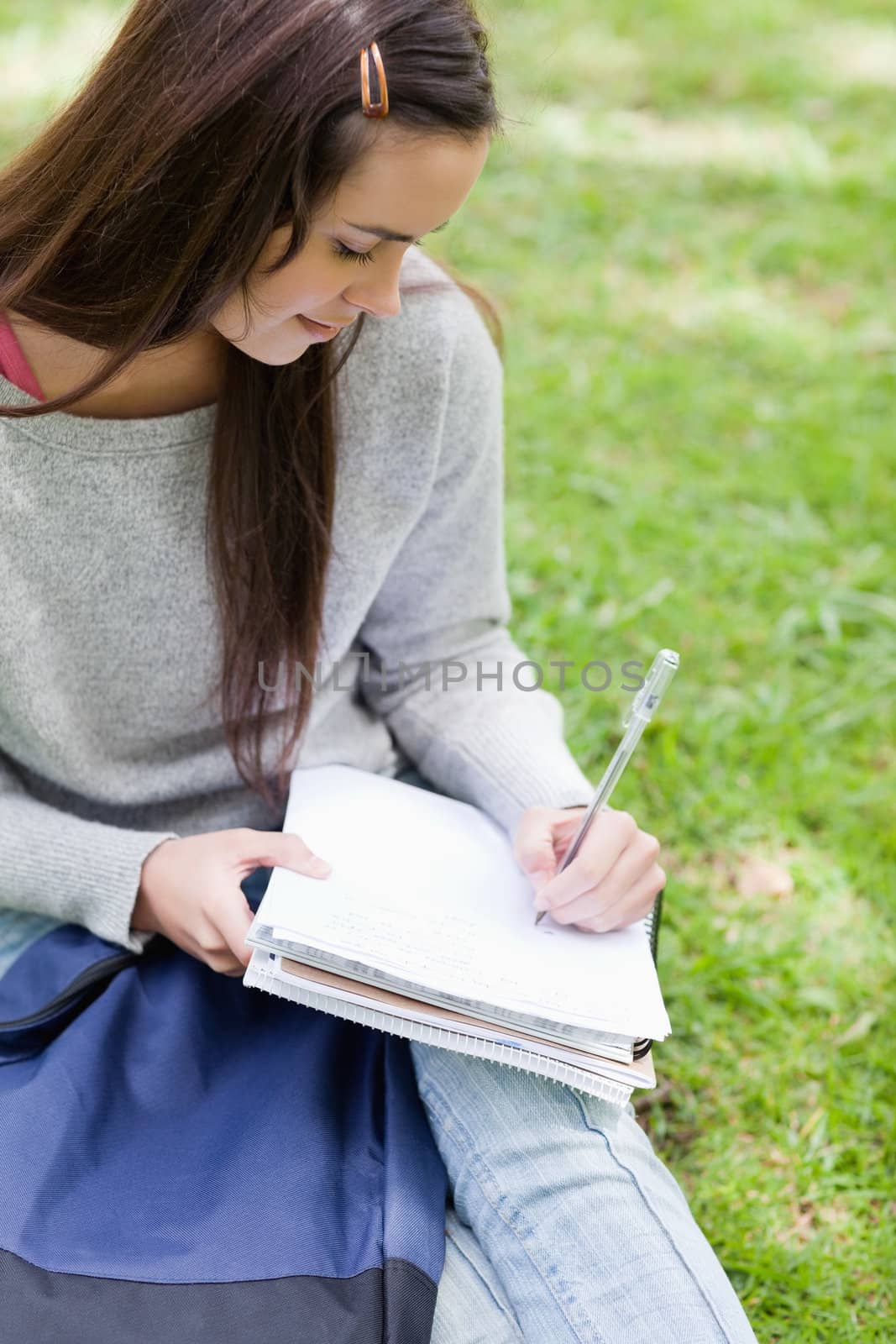 Overhead view of a young girl sitting in the countryside with her school books