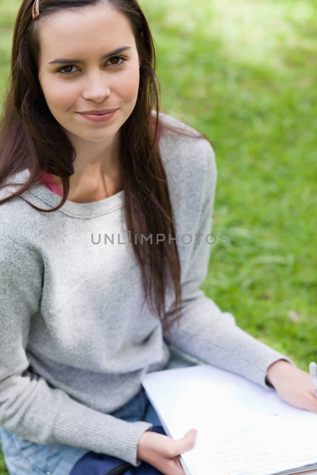 Young calm girl sitting in a park while holding school books by Wavebreakmedia