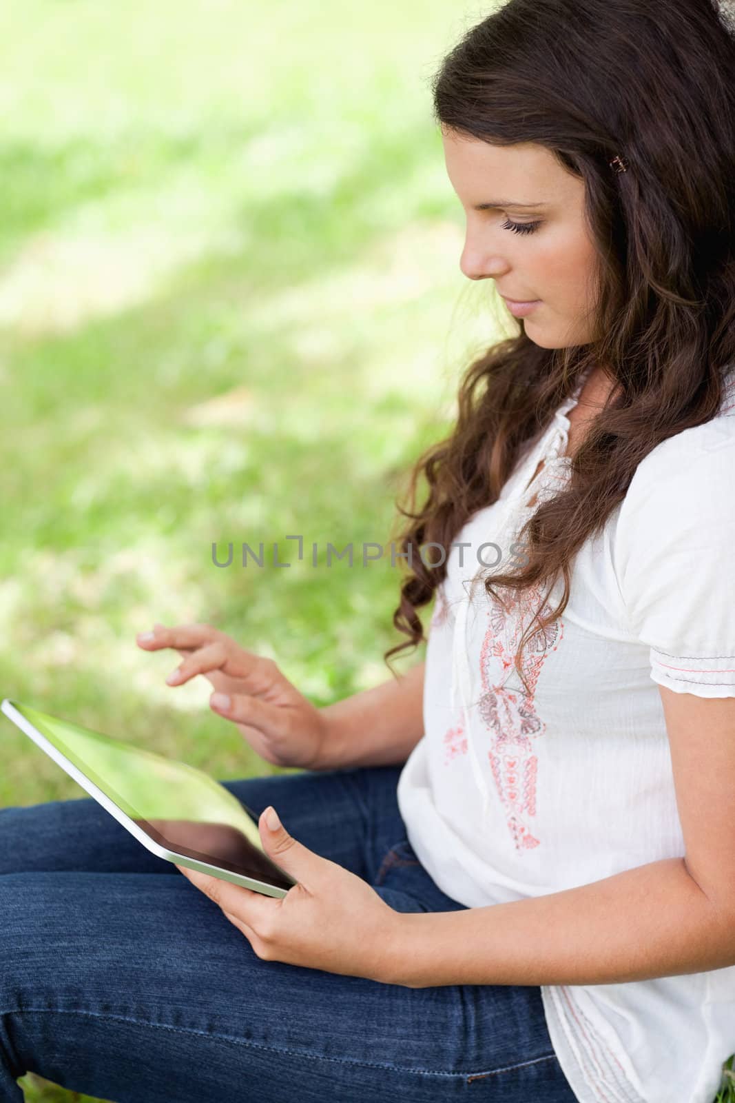 Young woman sitting in the countryside while using her tablet pc by Wavebreakmedia