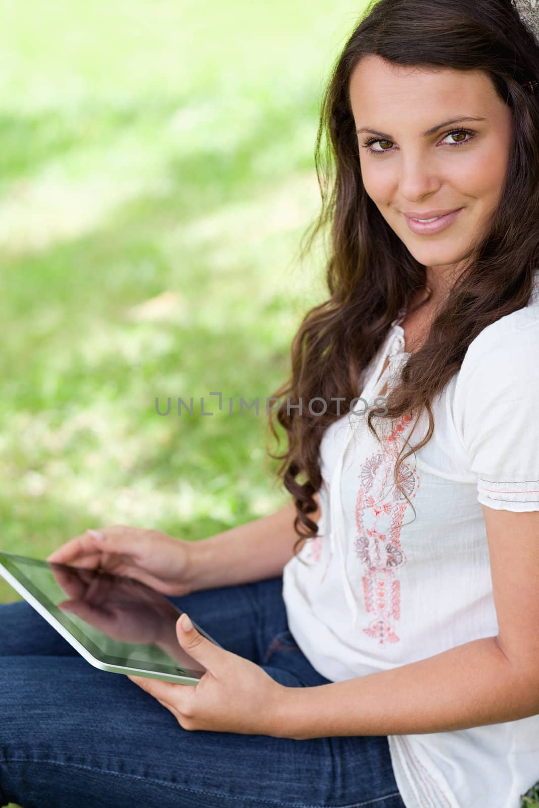 Young smiling woman looking at the camera while sitting down by Wavebreakmedia