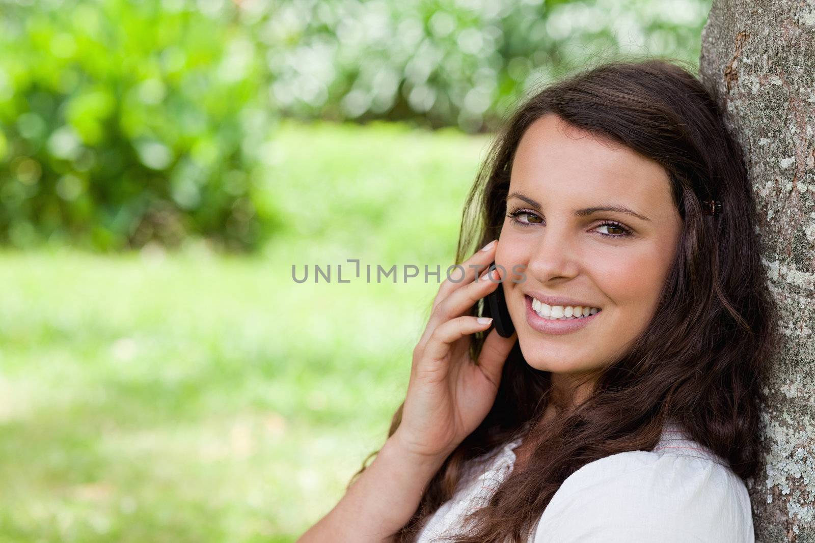 Young smiling woman talking on the phone while looking at the ca by Wavebreakmedia