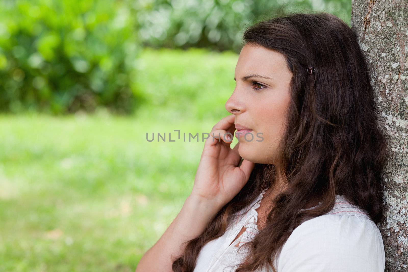 Young serious woman talking on the phone while leaning against a by Wavebreakmedia