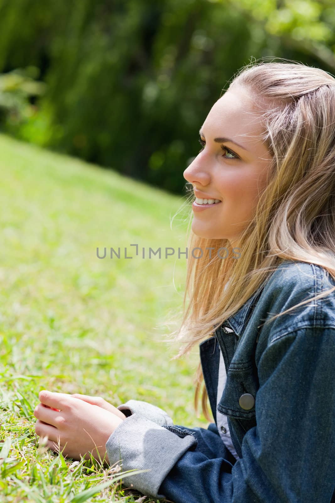 Young girl lying on the grass in the countryside while showing a great smile