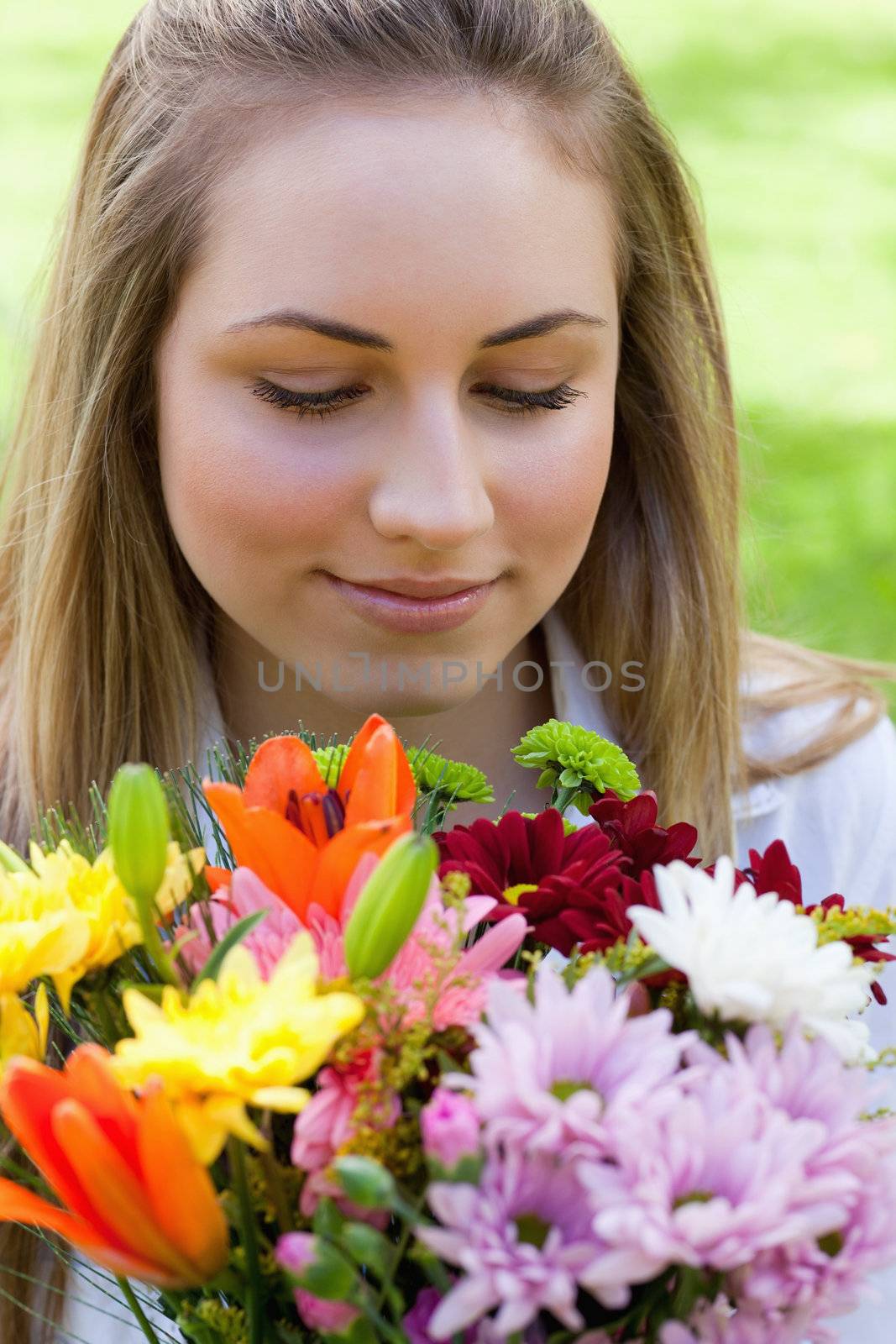 Young peaceful woman smelling a bunch of flowers while closing h by Wavebreakmedia