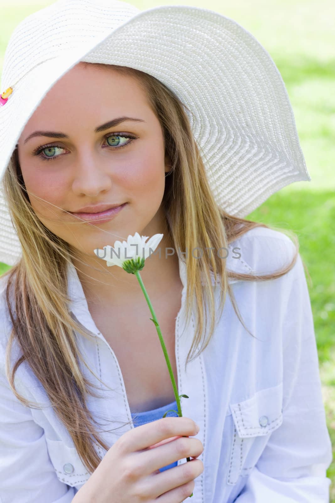 Young peaceful girl holding a white flower in a park by Wavebreakmedia