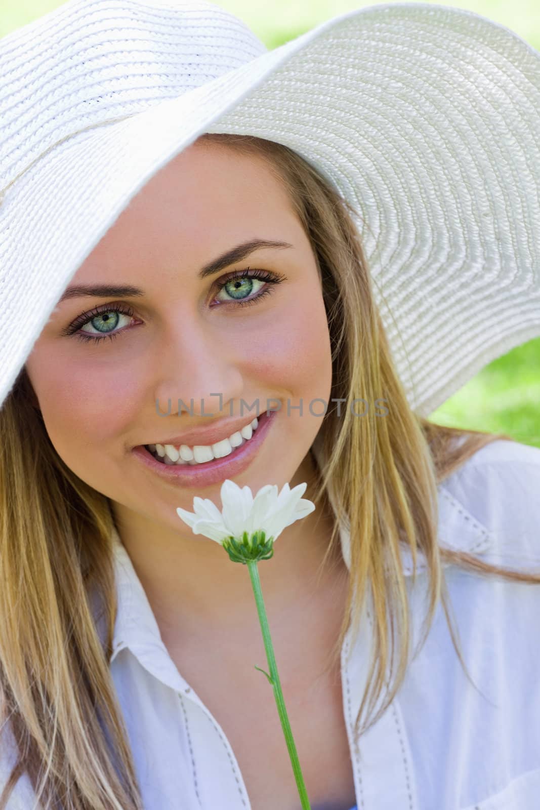 Young attractive blonde girl wearing a white hat while holding a by Wavebreakmedia