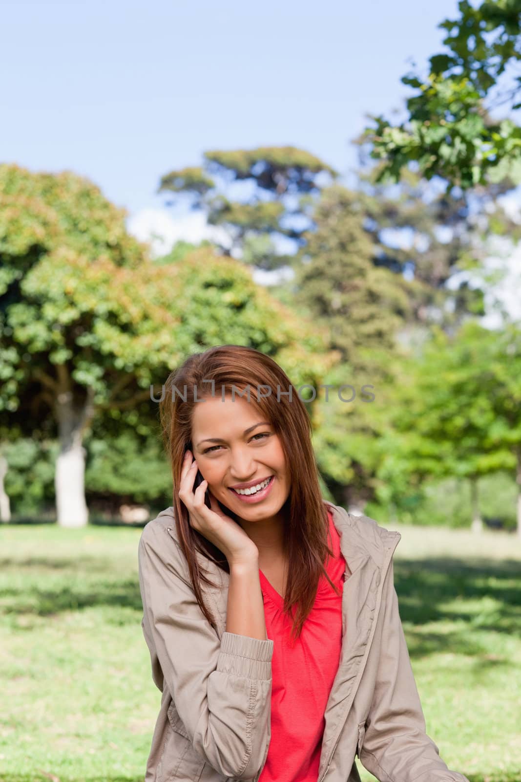 Young woman happy smiling while looking into the camera in an open grassland area