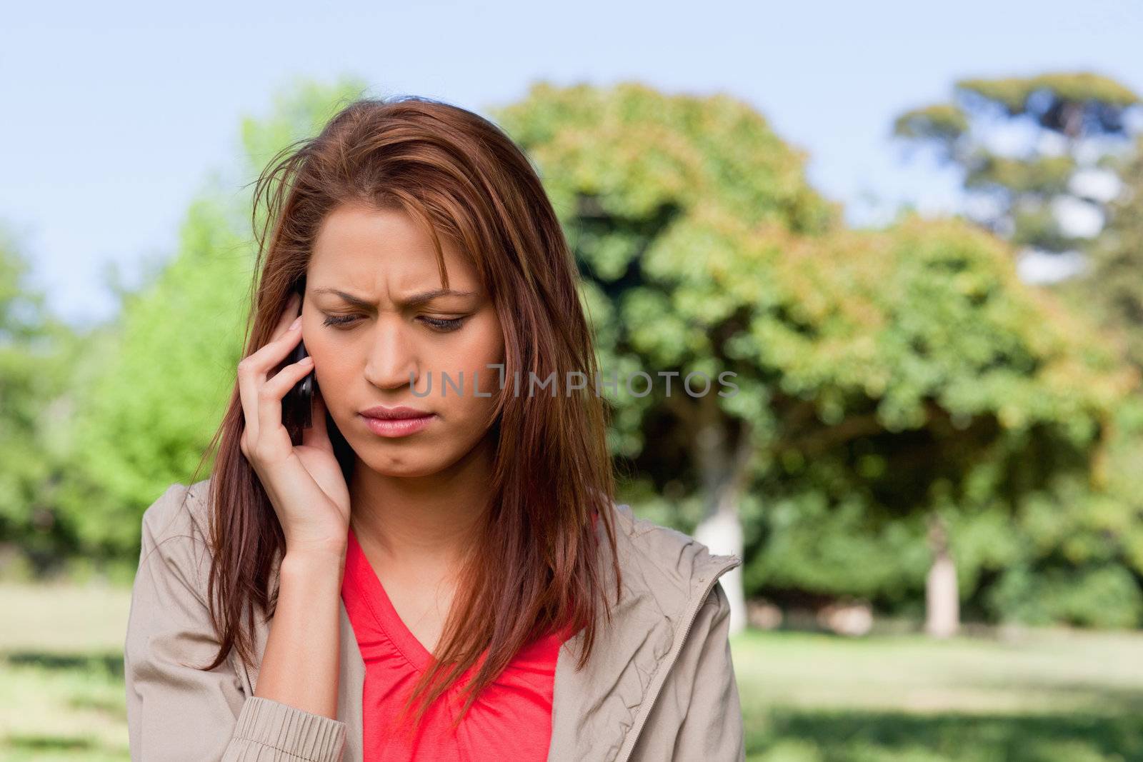 Woman looking downwards while making a call in a bright grassland area