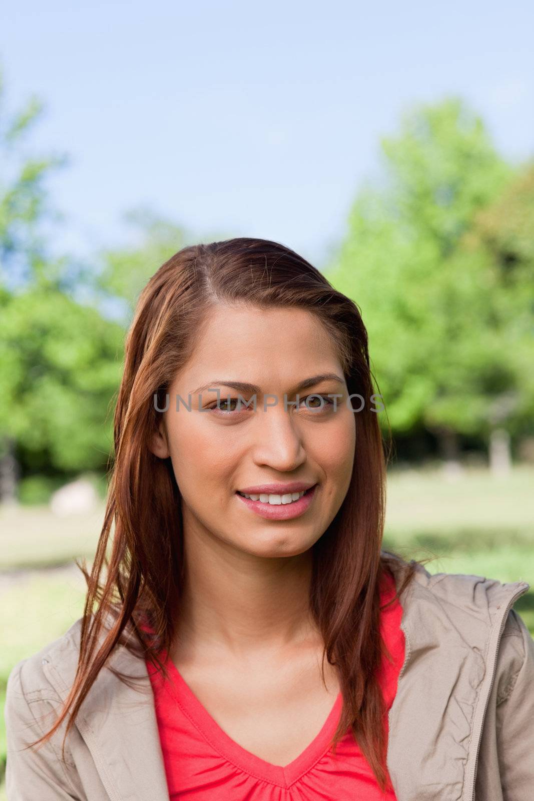 Woman smiling as she looks straight ahead in a sunny grassland environment