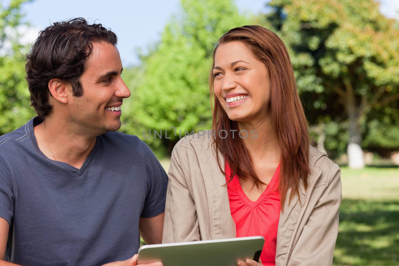 Woman looking at her friend while she is holding a tablet by Wavebreakmedia