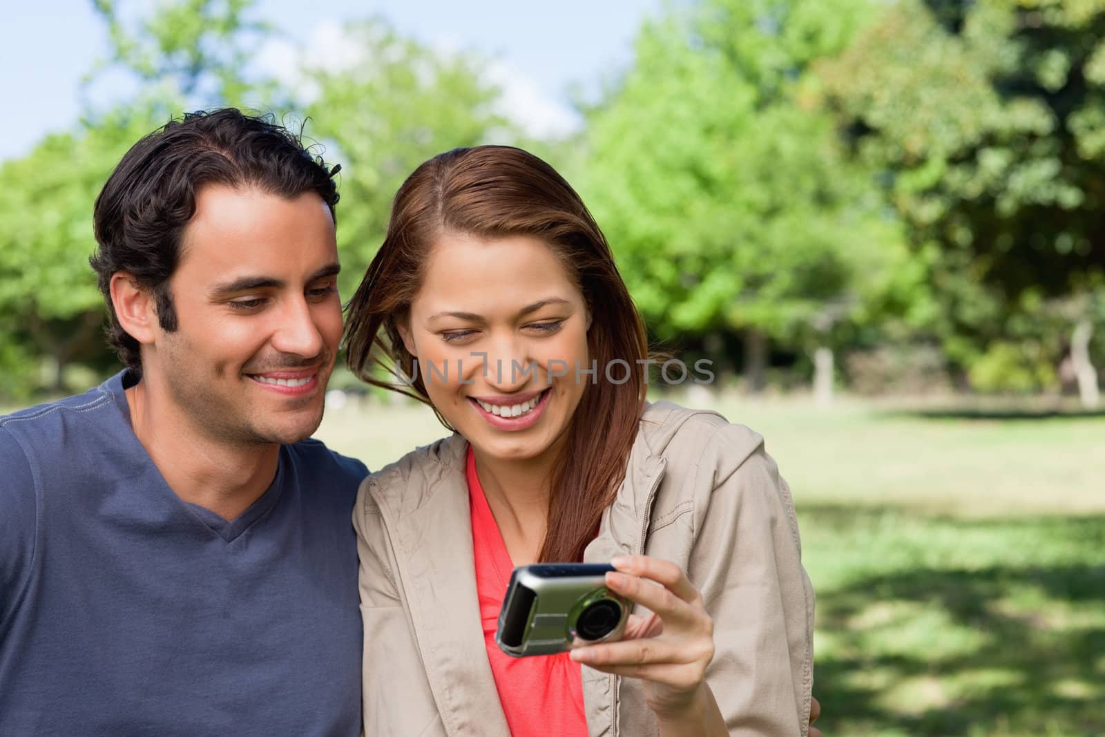 Woman and her friend looking at pictures on a camera in a bright park