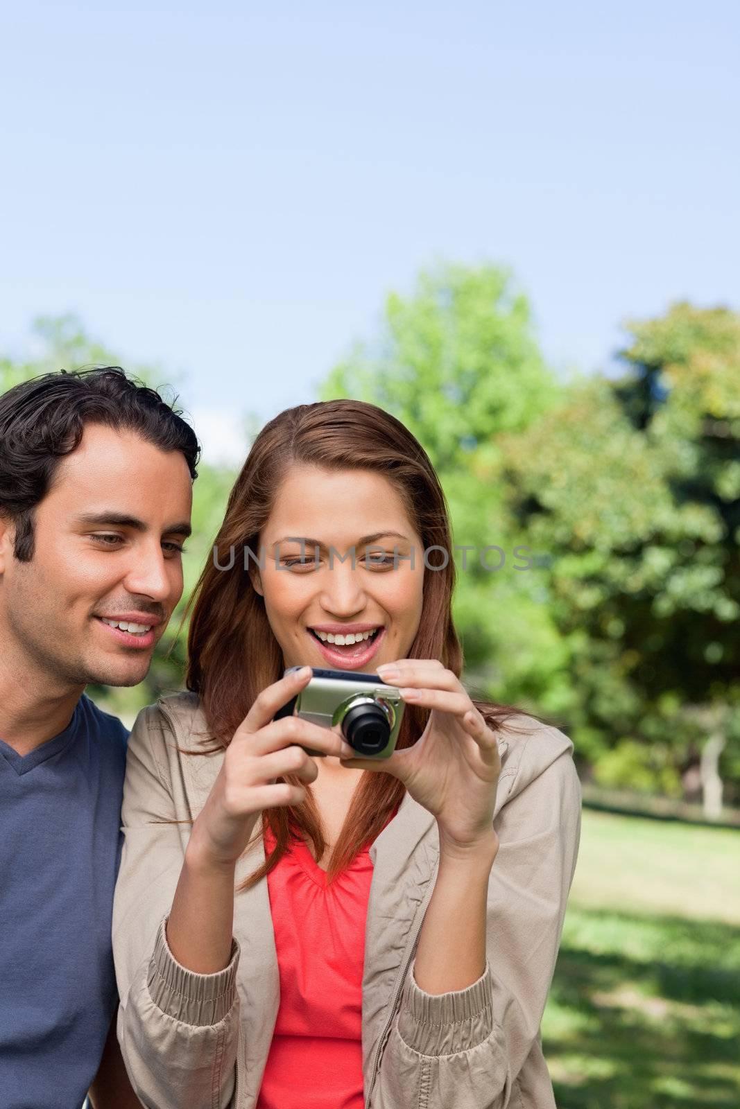 Two friends looking at the photo collection in her camera by Wavebreakmedia