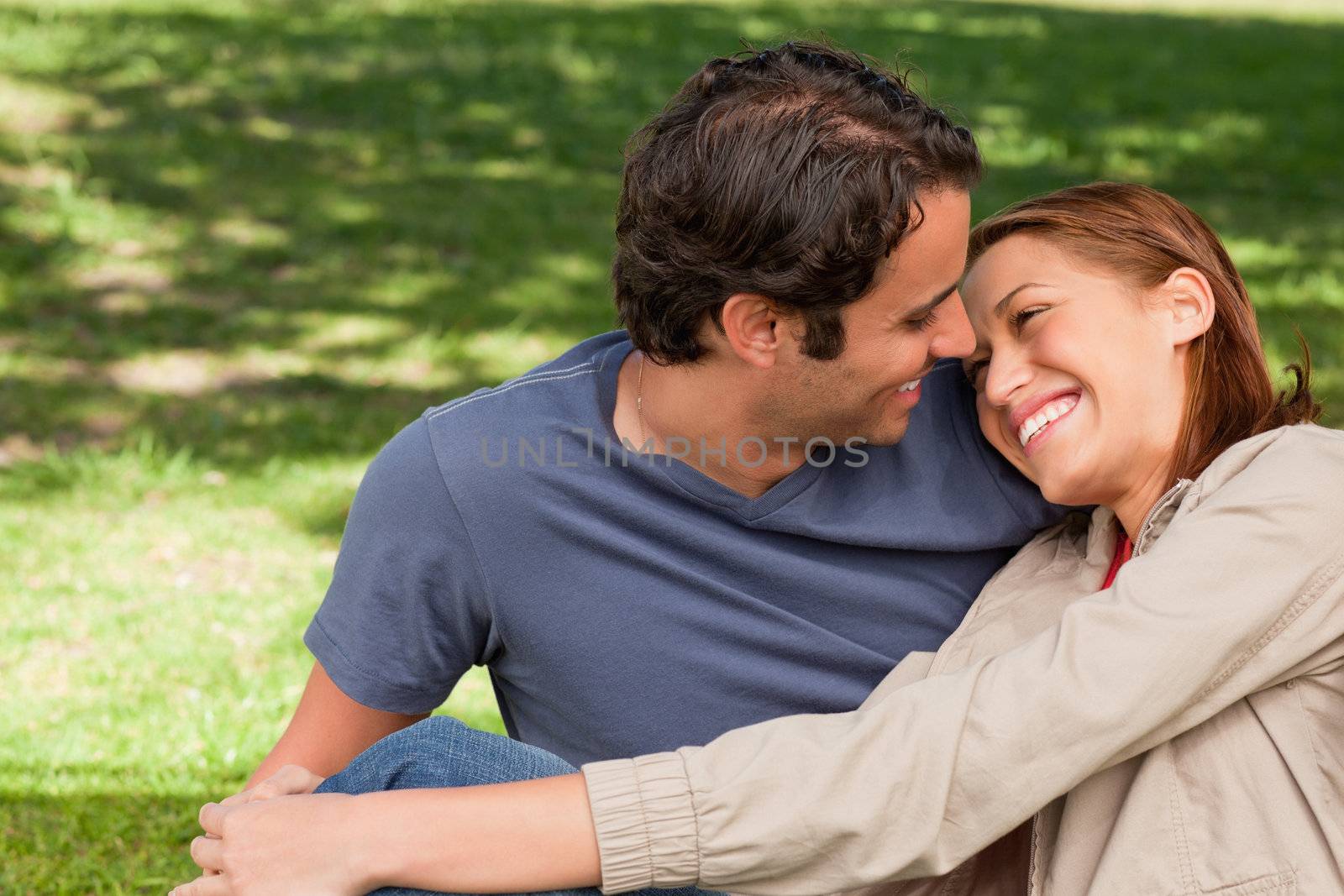 Two friends smiling while they look look into each others eyes as the woman rests her head on the mans shoulder