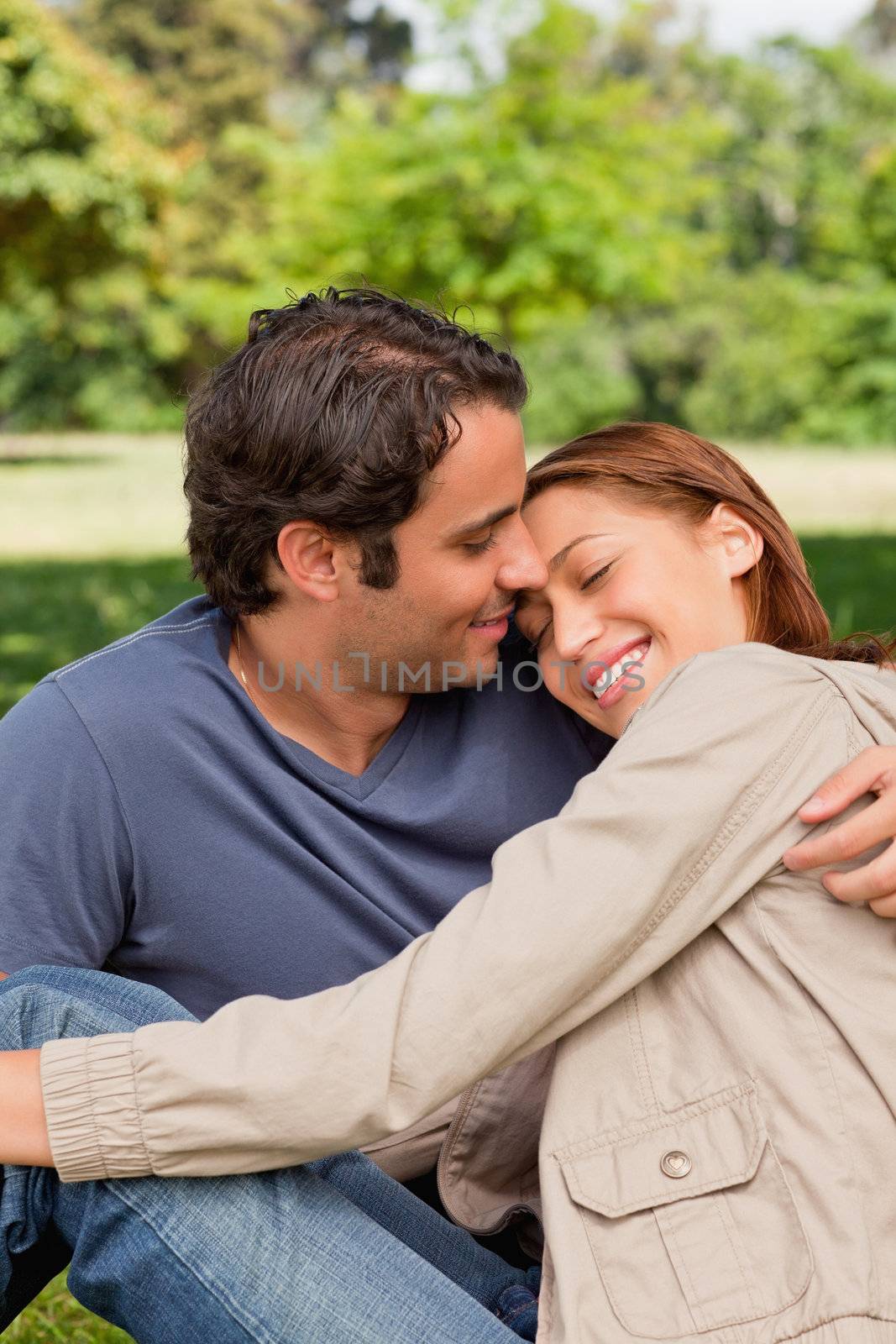 Man smiling as his friend rests her head on his shoulders by Wavebreakmedia