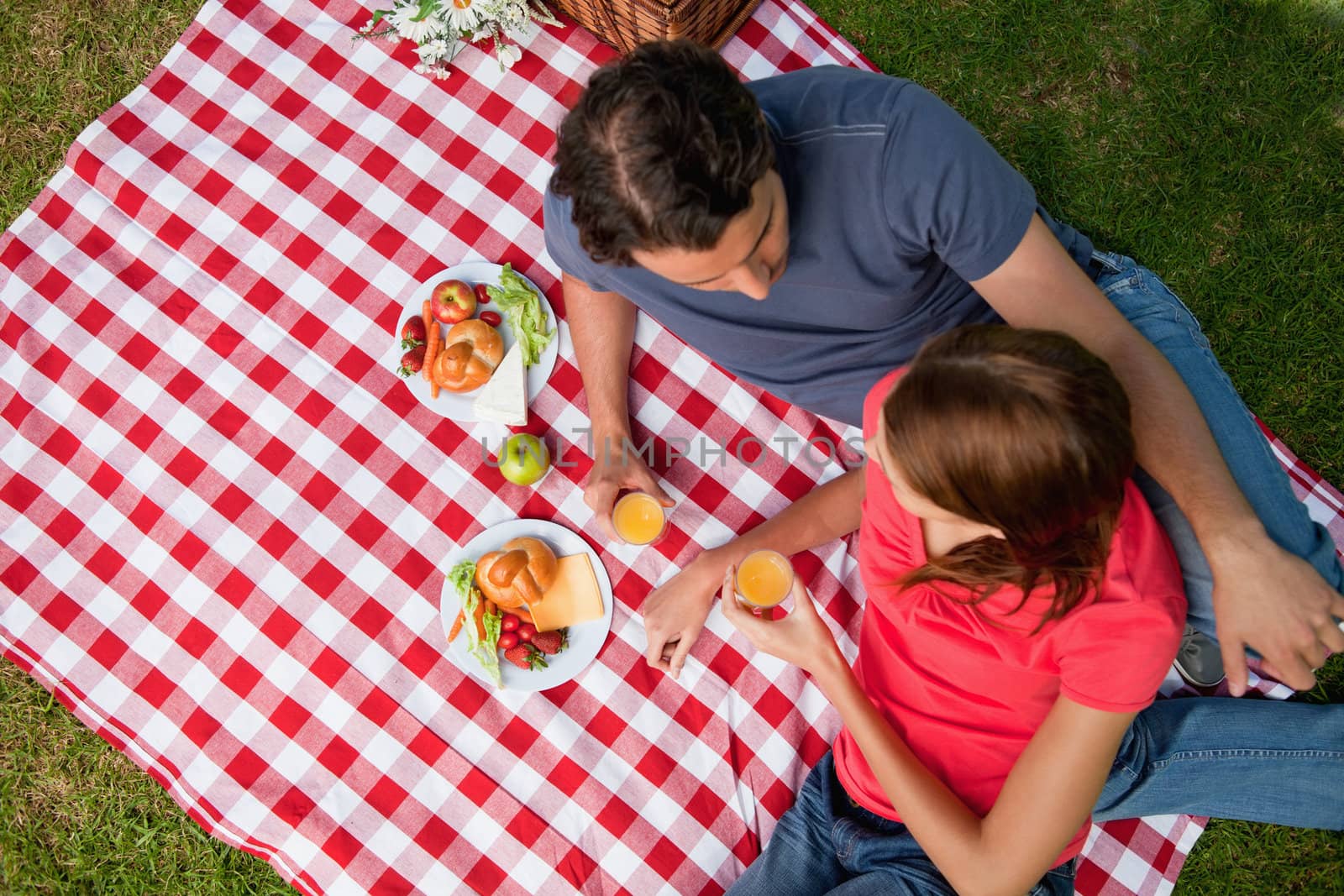 Elevated view of two friends lying on a blanket with a picnic by Wavebreakmedia