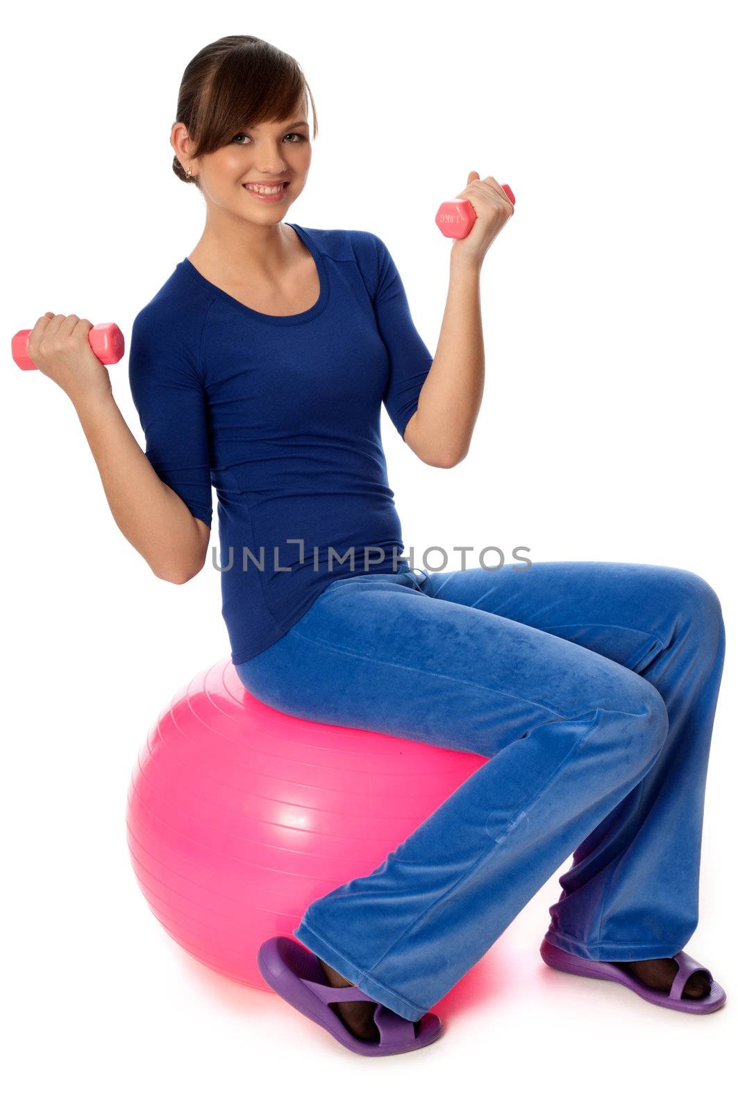 Instructor taking exercise class using ball and dumbbells at gym