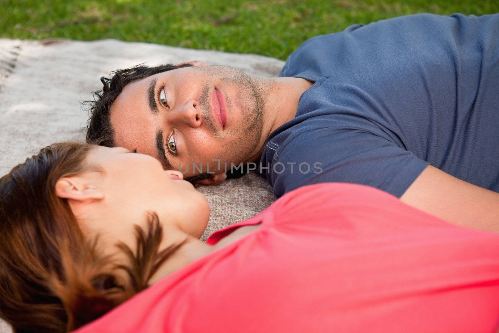Man looking into his friends eyes while lying on a quilt by Wavebreakmedia