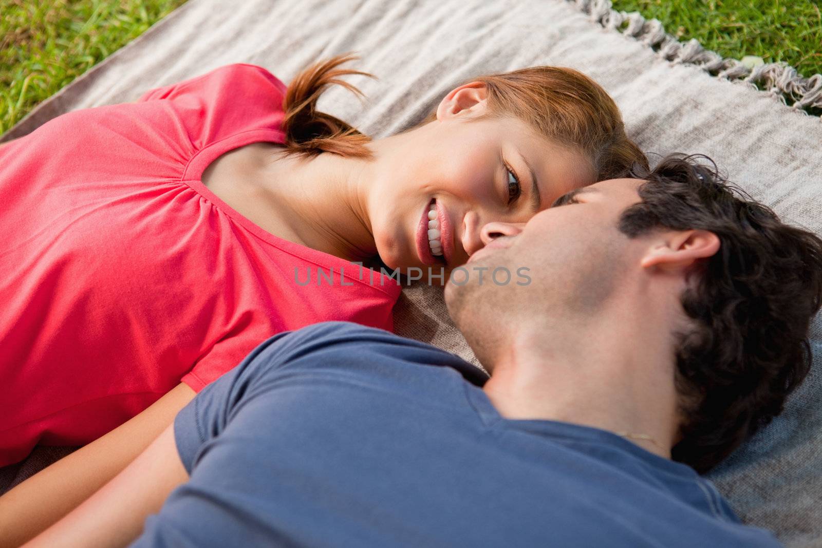 Smiling woman looking into her friends eyes while lying on a grey quilt