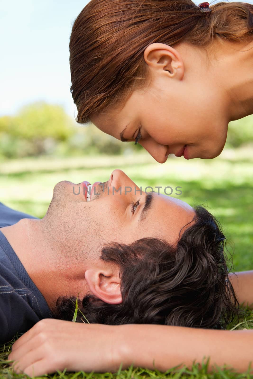 Woman looking down towards her friend who is smiling while lying on the grass