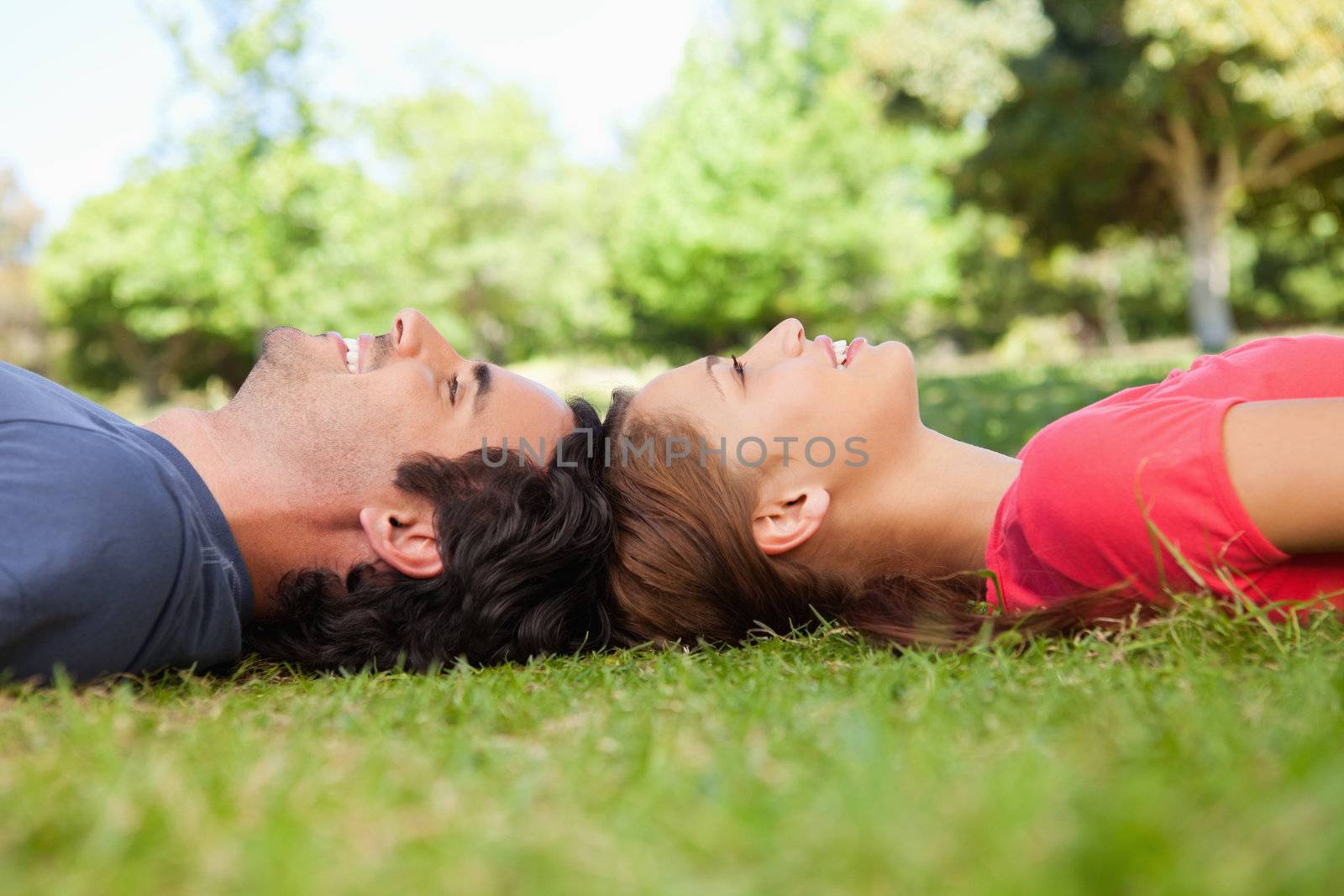 Two friends smiling while lying head to head on the grass
