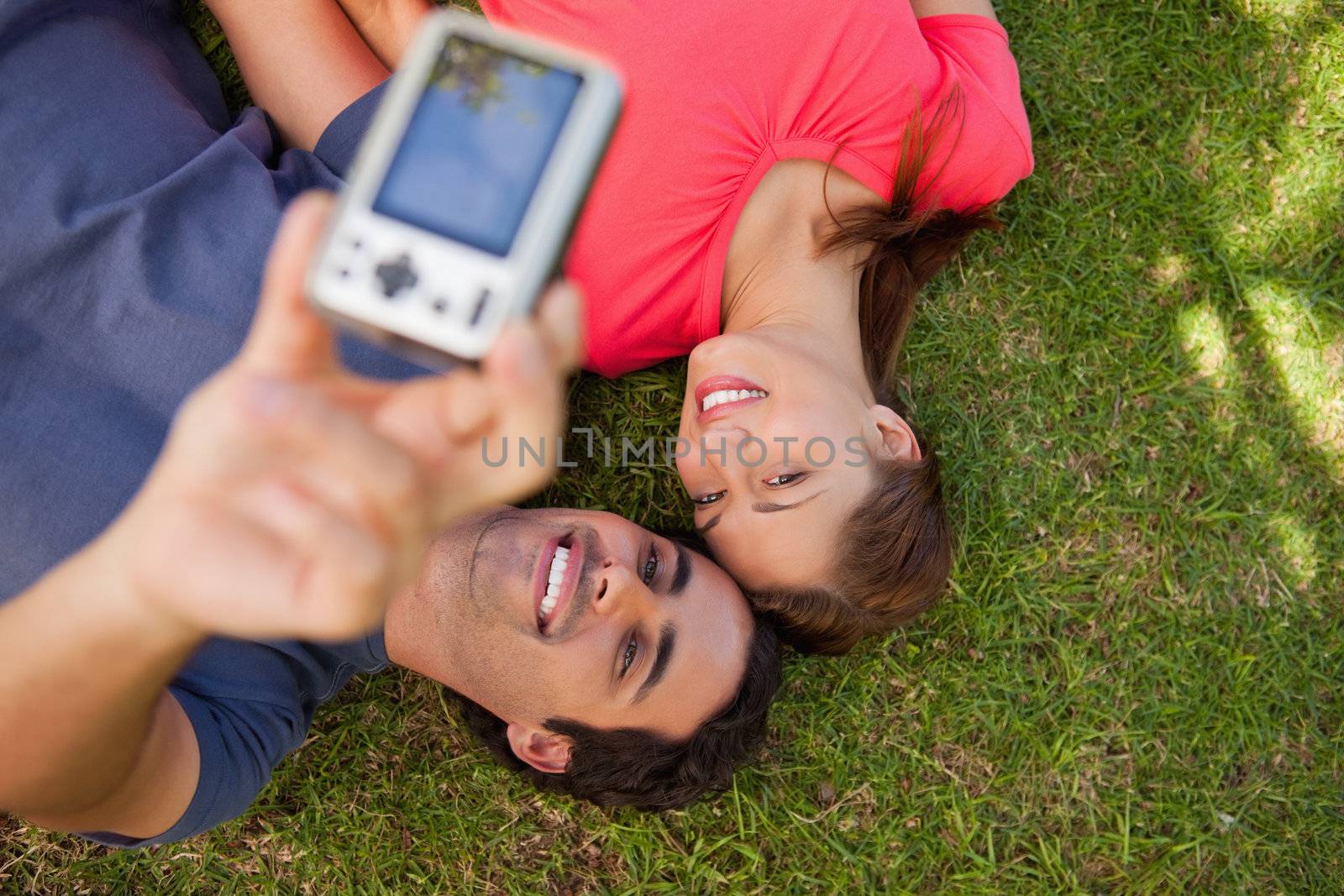 Two friends using a camera while lying side by side by Wavebreakmedia