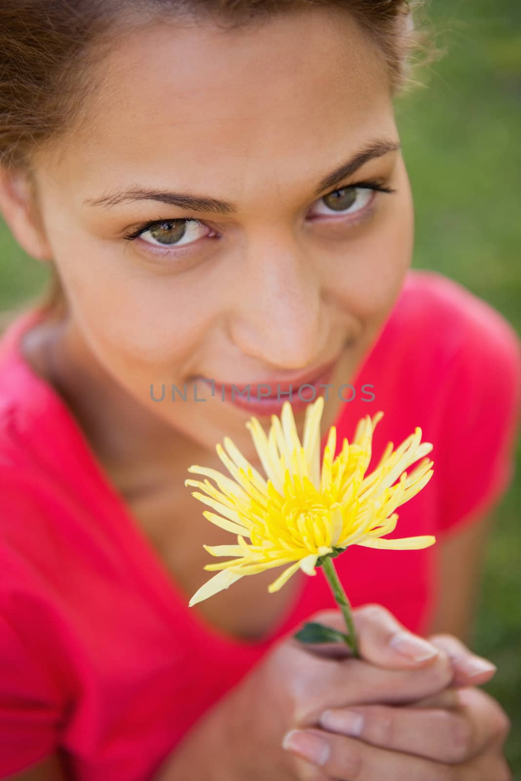 Woman looking upwards while holding a yellow flower by Wavebreakmedia