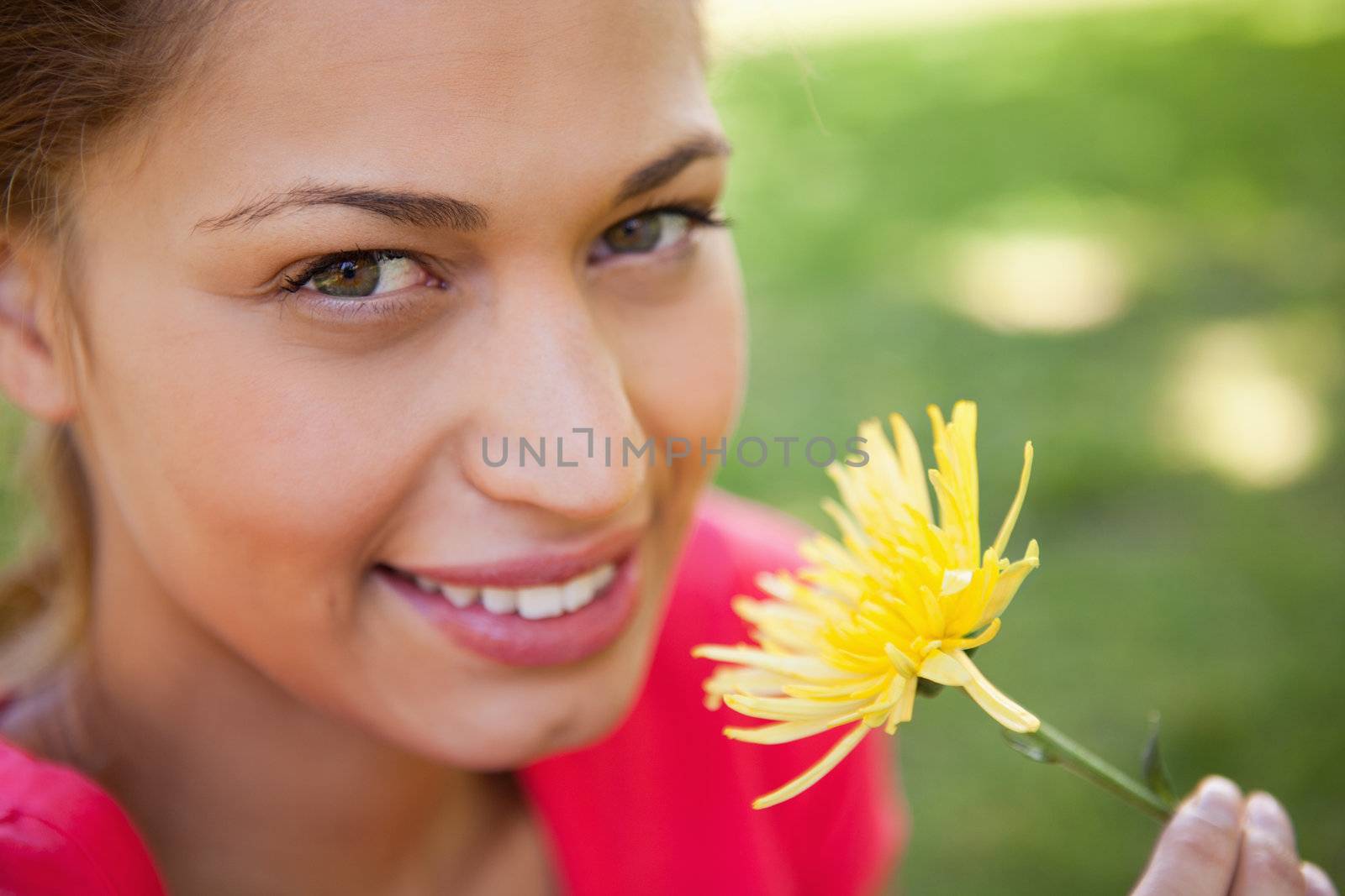 Woman smiling as she looks upwards while holding a yellow flower by Wavebreakmedia