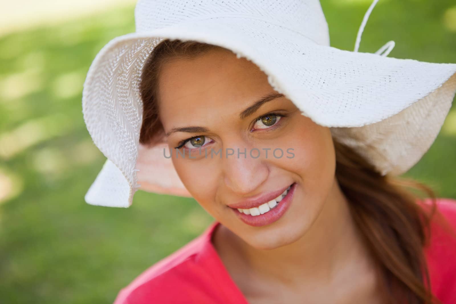 Woman looking ahead while smiling and wearing a white hat