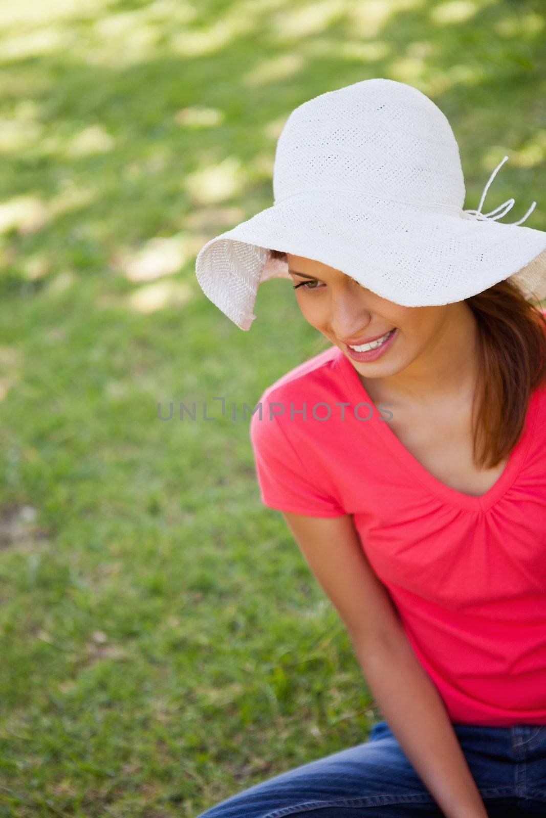 Woman smiling while wearing a white hat as she sits in the grass