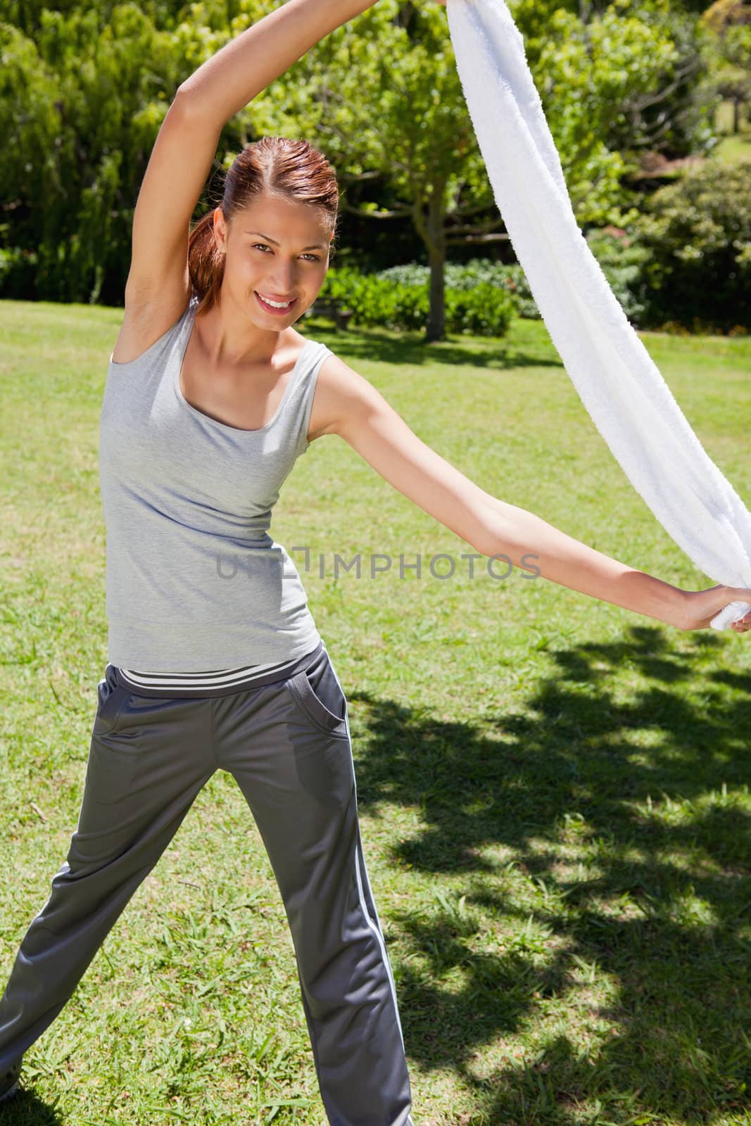 Woman smiling while stretching as she holds her towel 