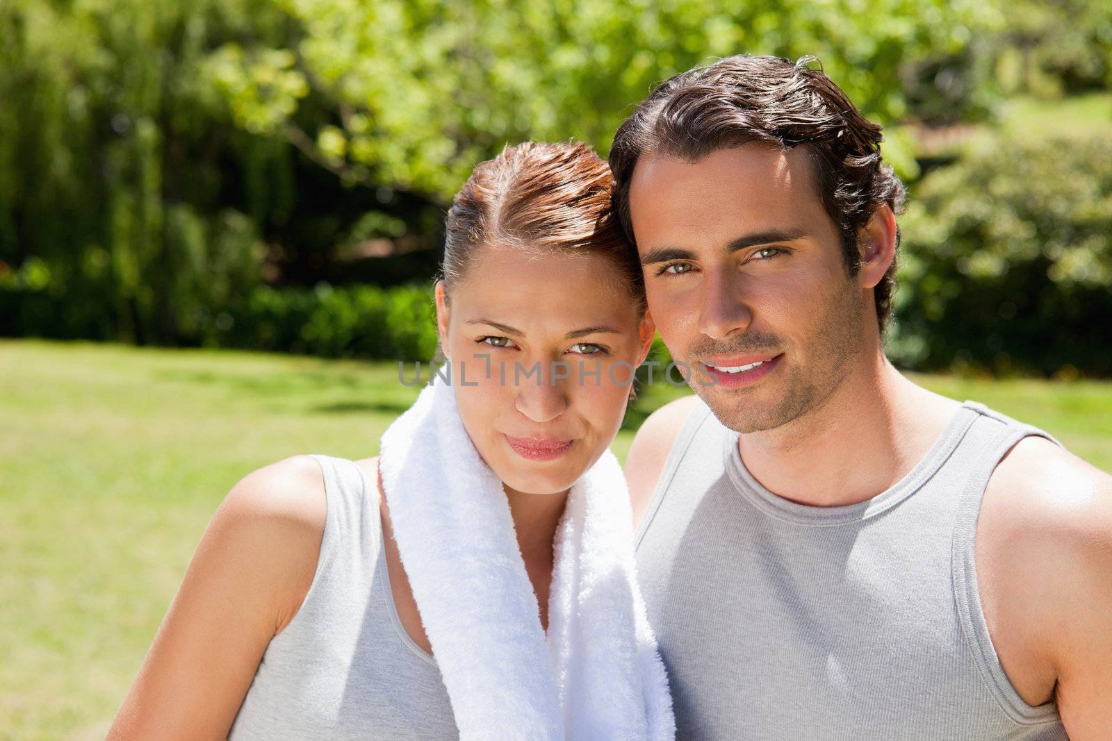Woman with a white towel around her neck standing with a smiling man in workout gear