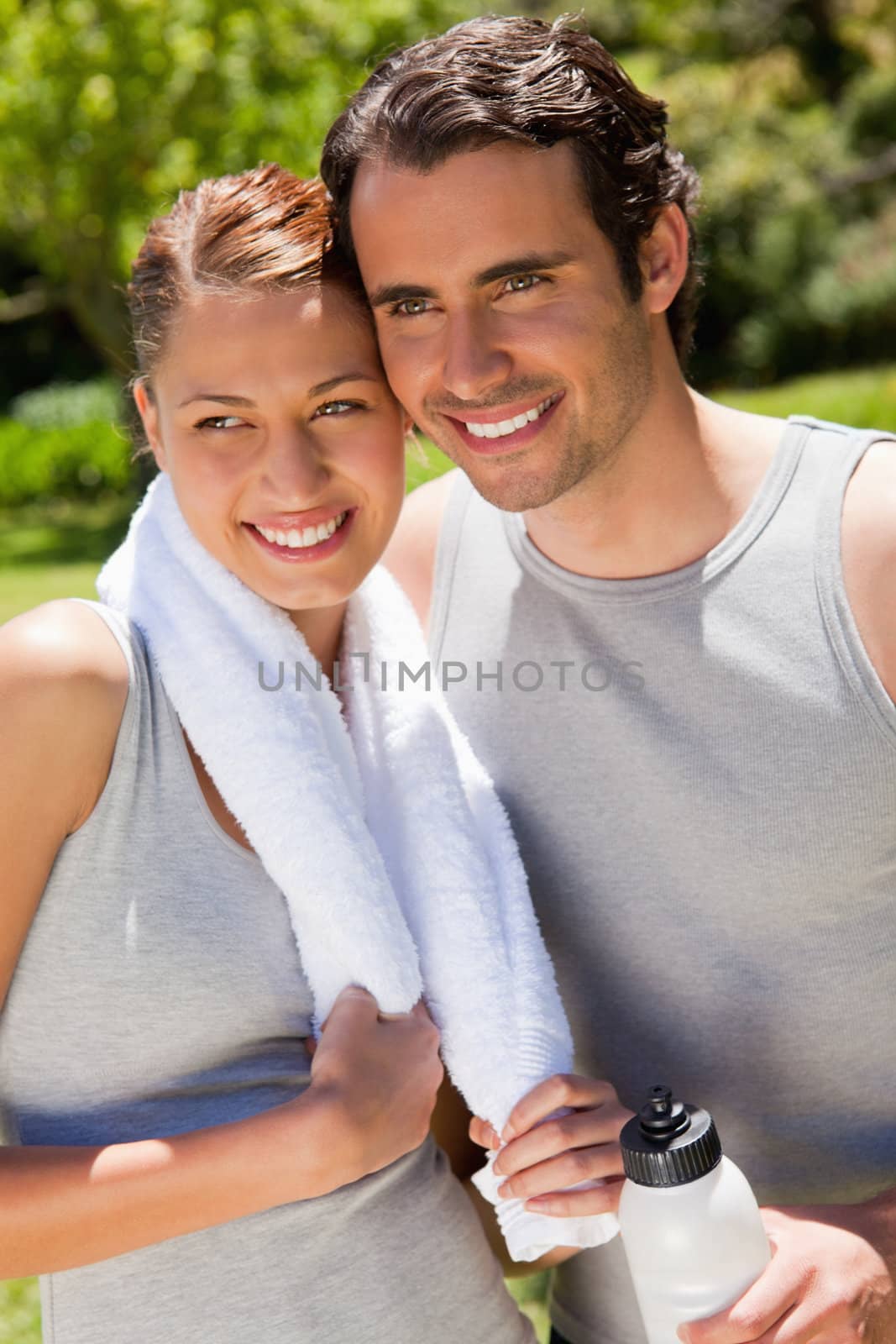 Man holding a white sports bottle smiling with a woman who is holding a towel 