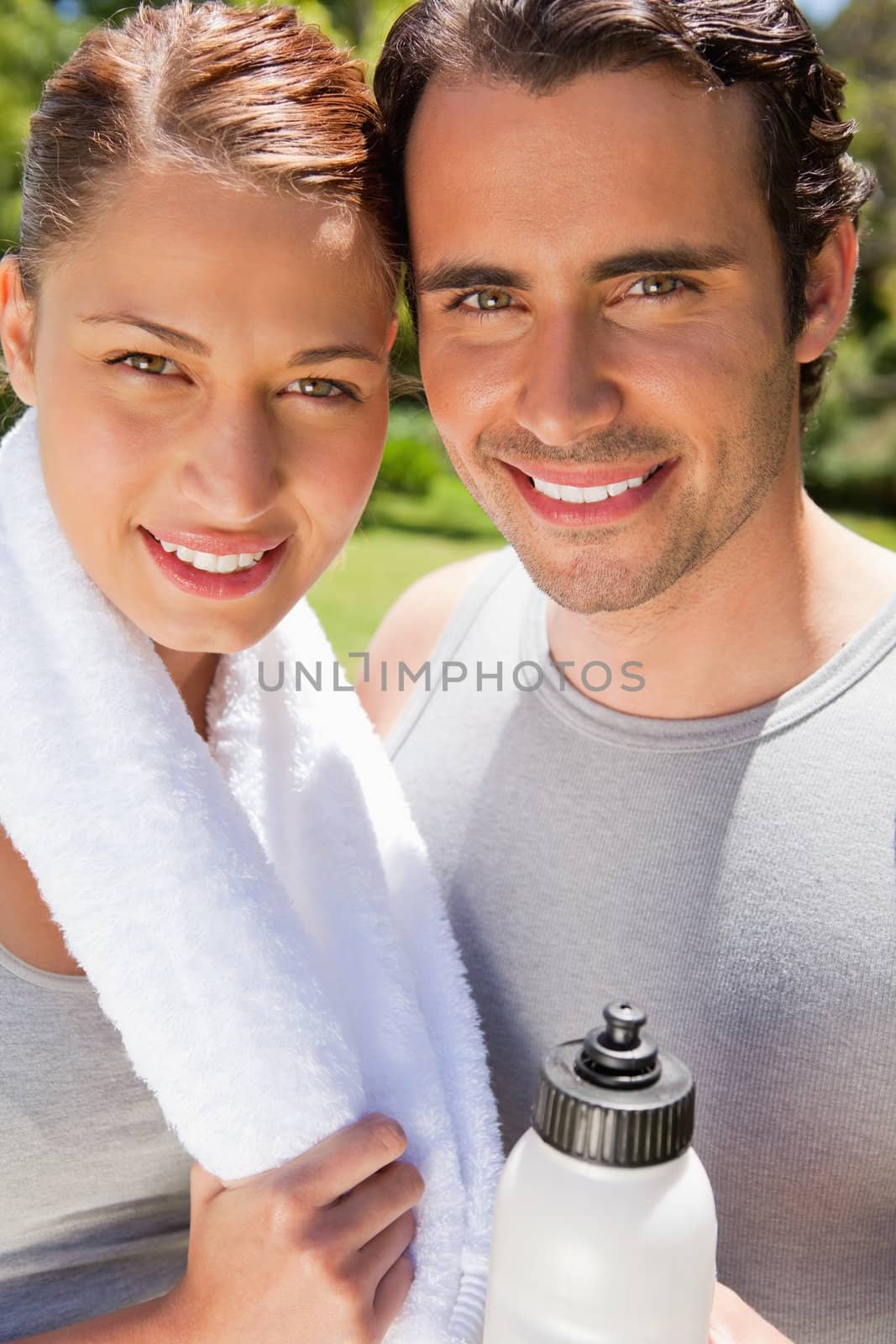 Smiling man holding a sports bottle with a woman who is smiling while holding a towel